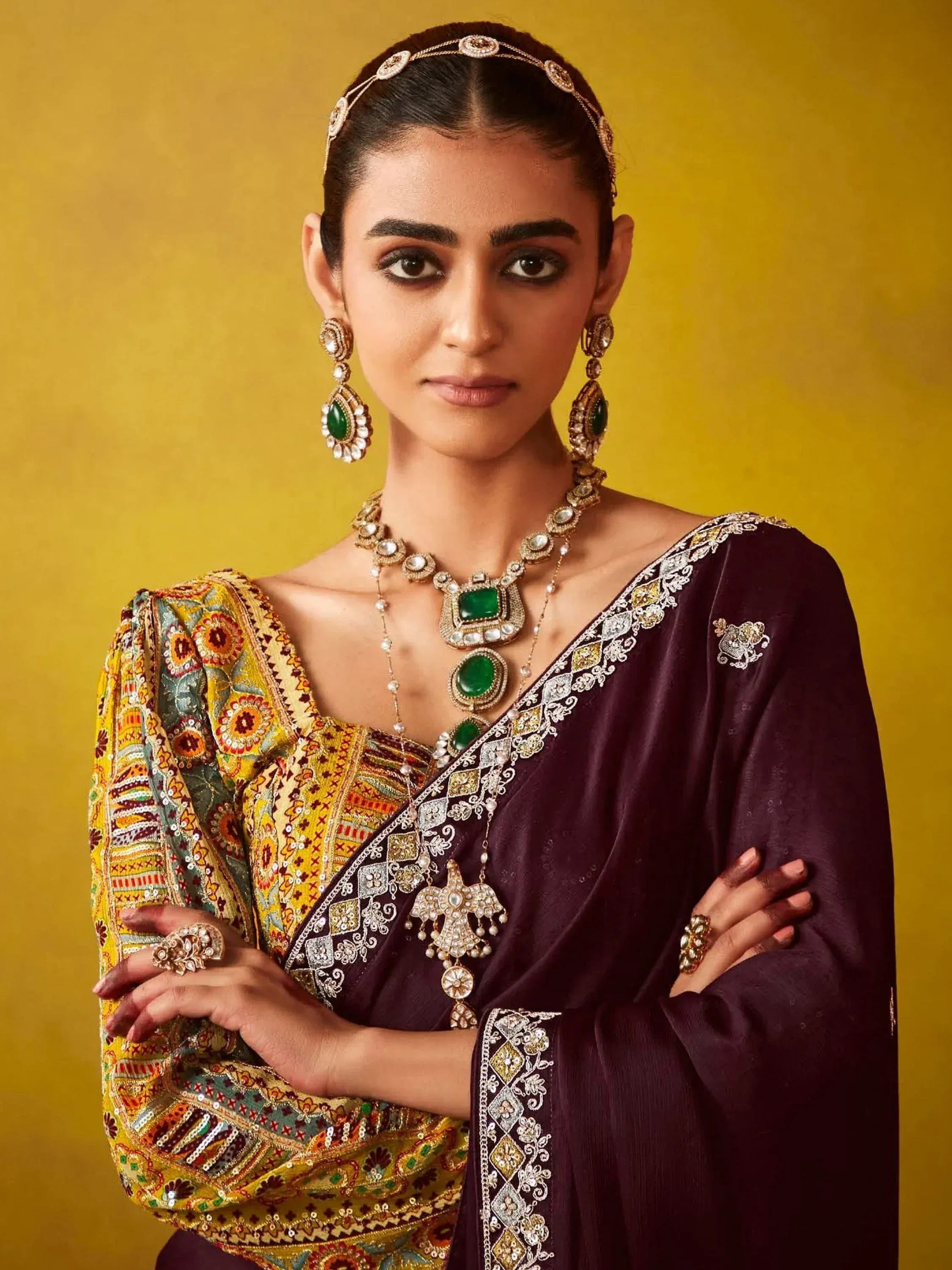 Woman in embroidered ethnic saree with green gemstone jewelry, traditional Indian attire