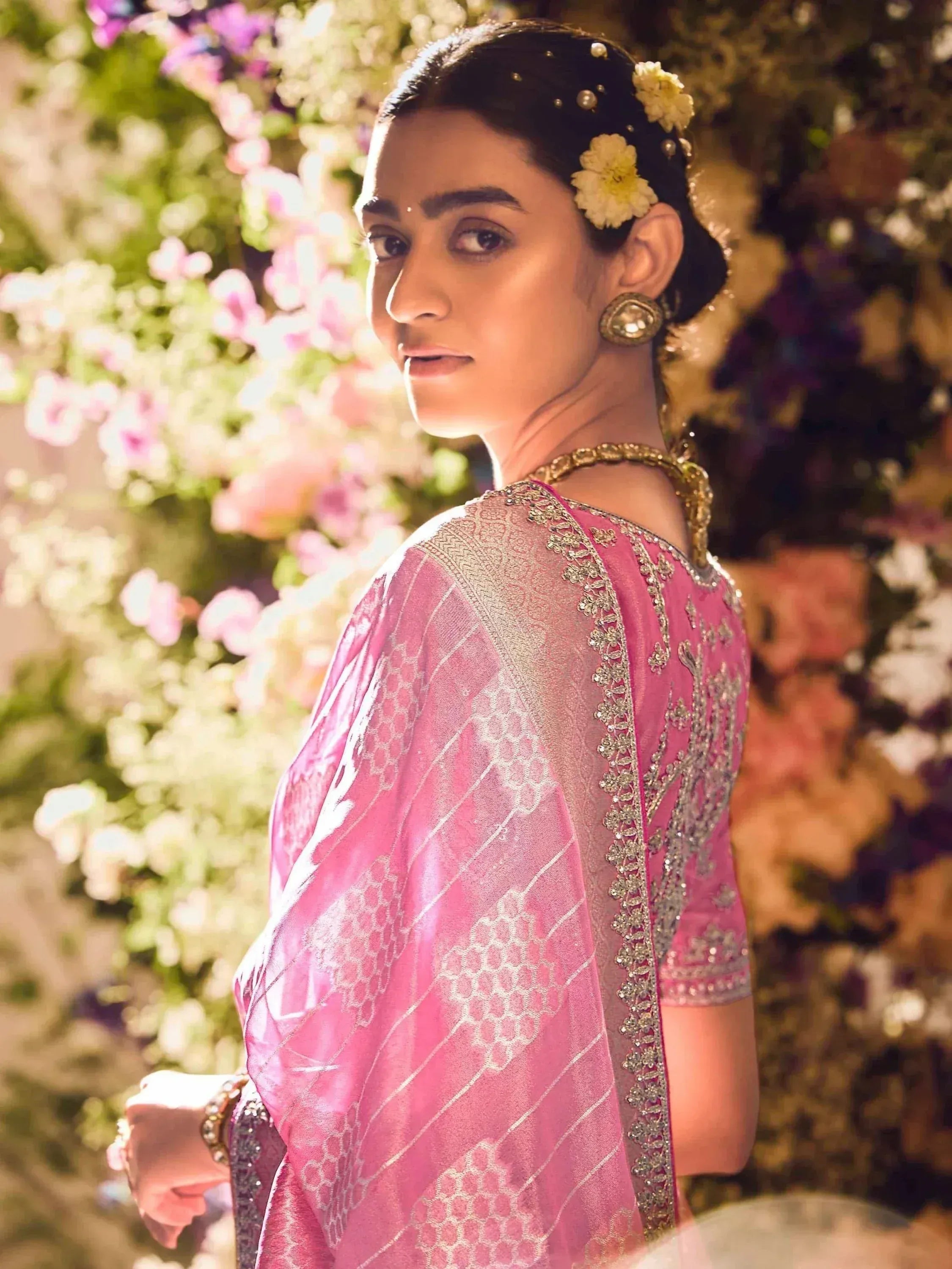 Woman in pink embroidered saree with floral hair accessories, ideal for Indian ethnic wear occasions