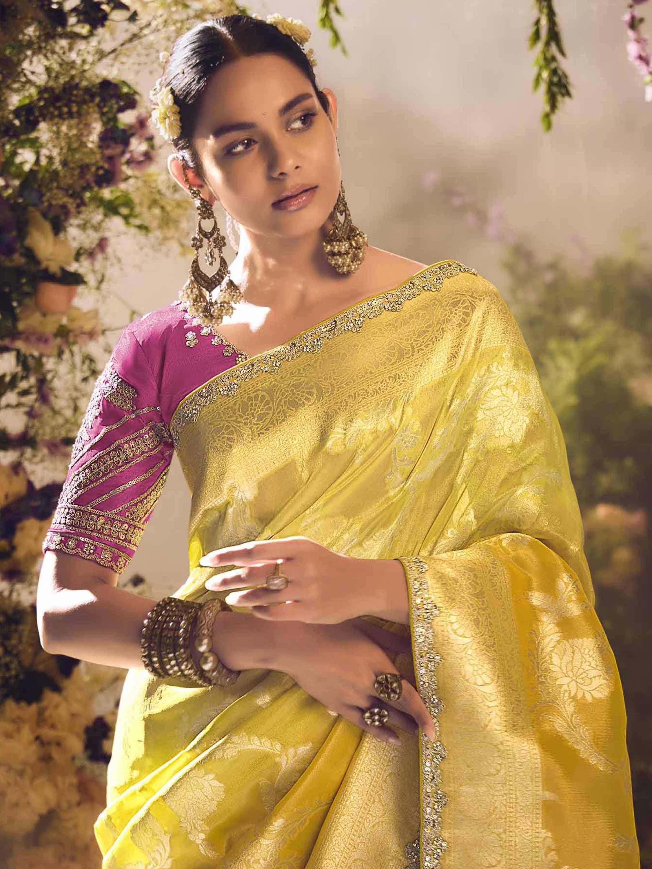 Yellow designer saree with purple blouse, floral embroidery, and gold jewelry for Indian ethnic wear