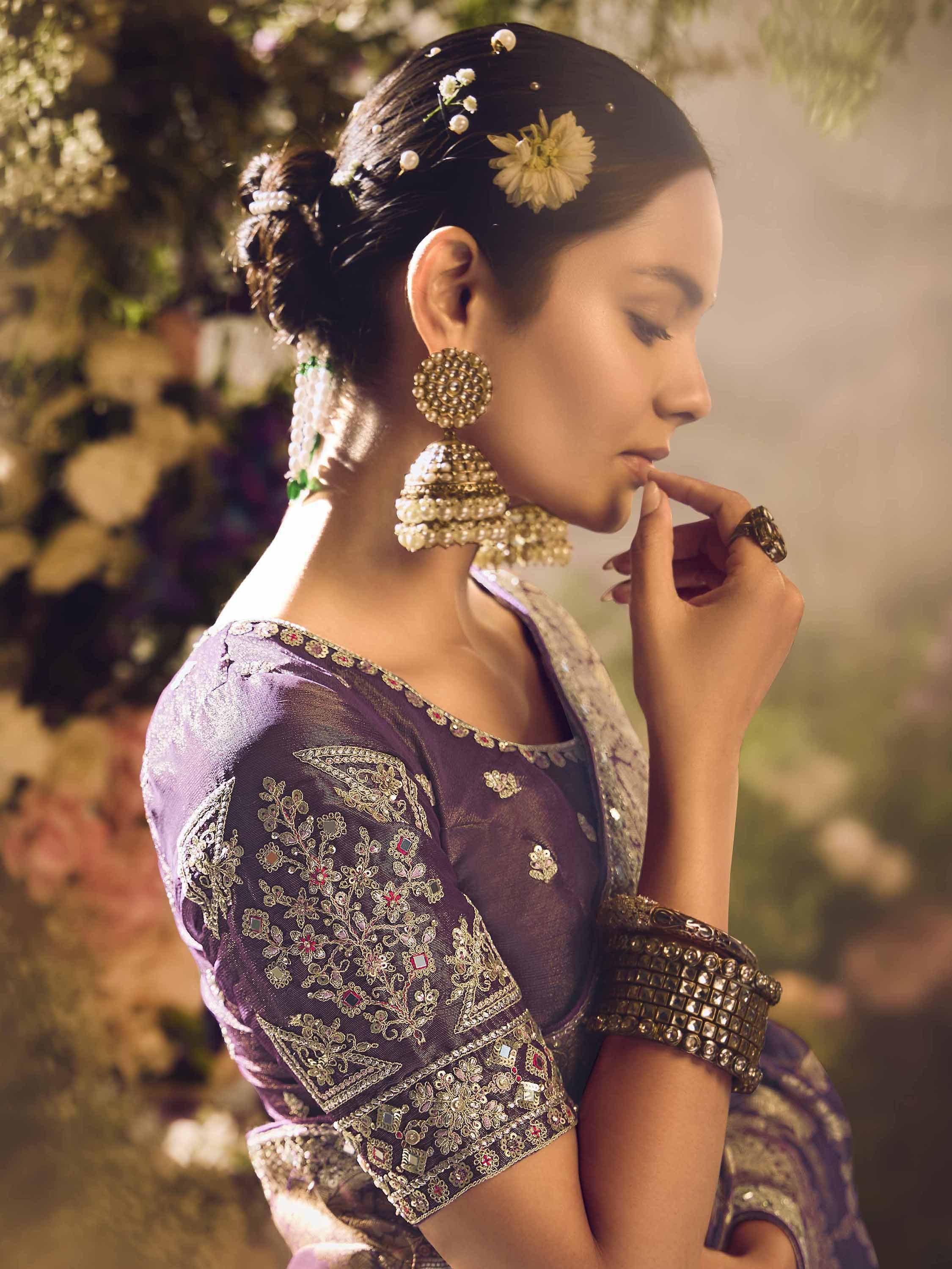 Elegant woman in purple embroidered ethnic wear with floral hair accessories and jhumka earrings