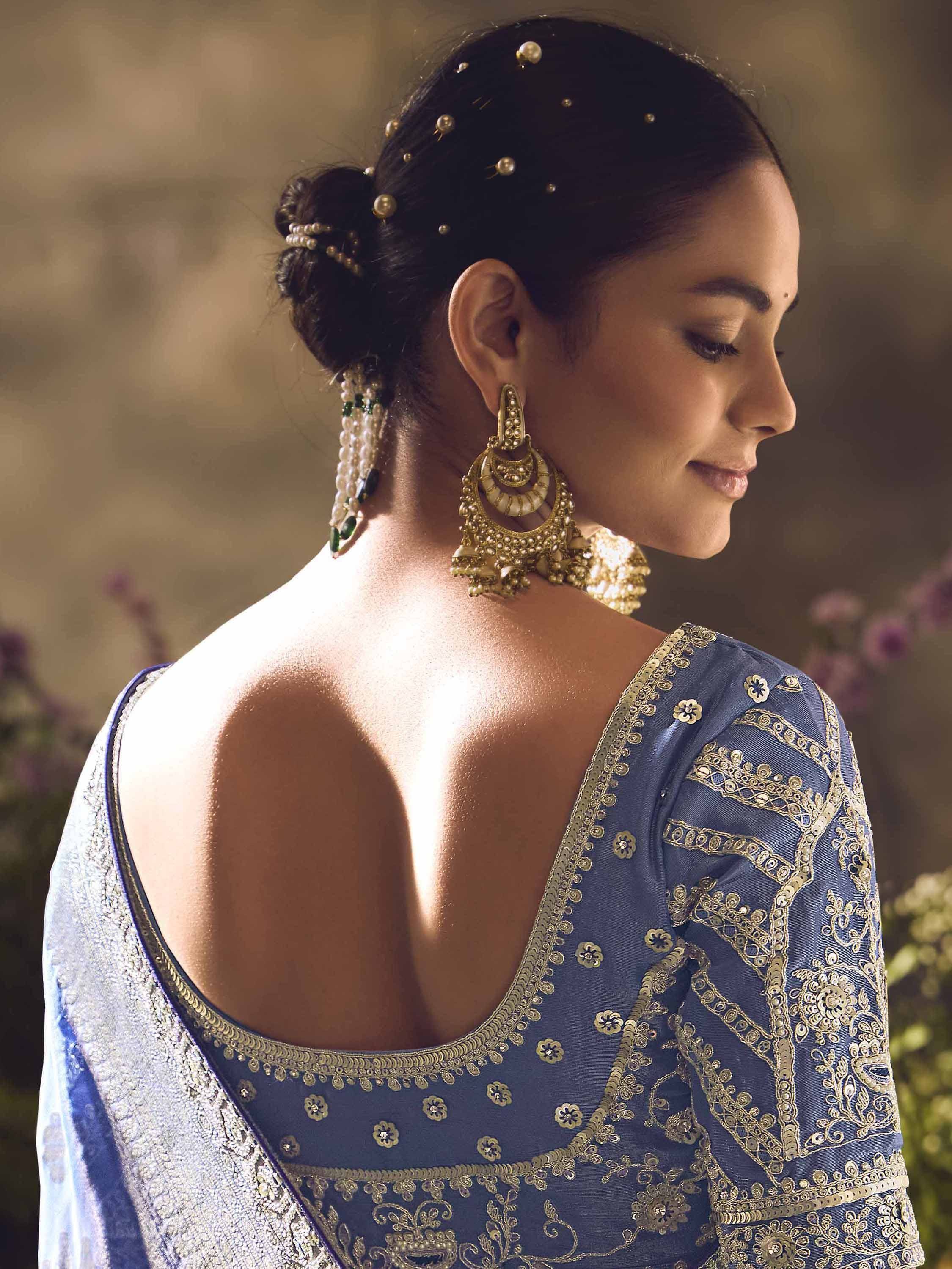 Blue embroidered lehenga choli with gold detailing, backless design, and traditional Indian jewelry