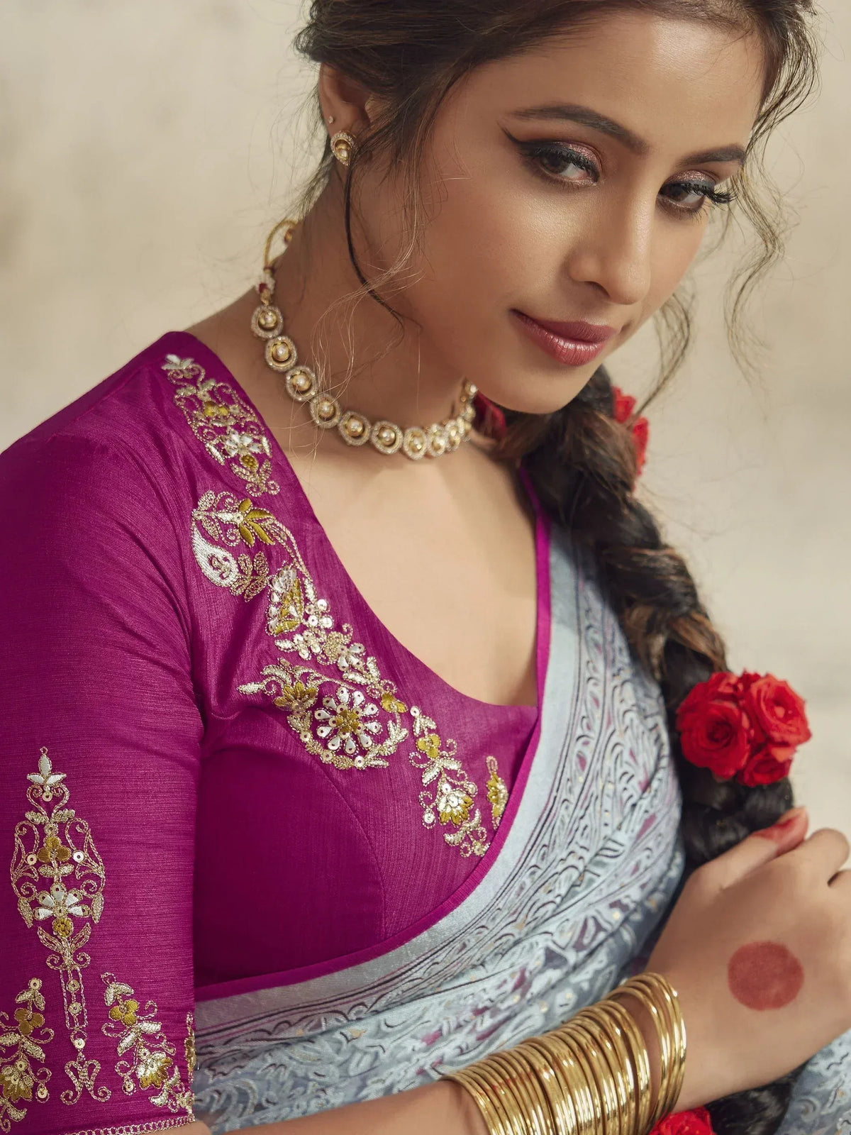 Woman in purple embroidered blouse with gold detailing, paired with light blue saree, traditional Indian ethnic wear