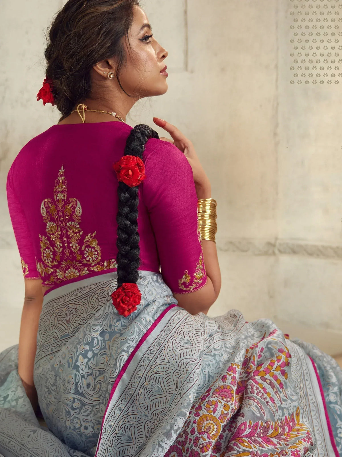 Woman in elegant Indian saree with pink embroidered blouse and floral braid, showcasing ethnic wear