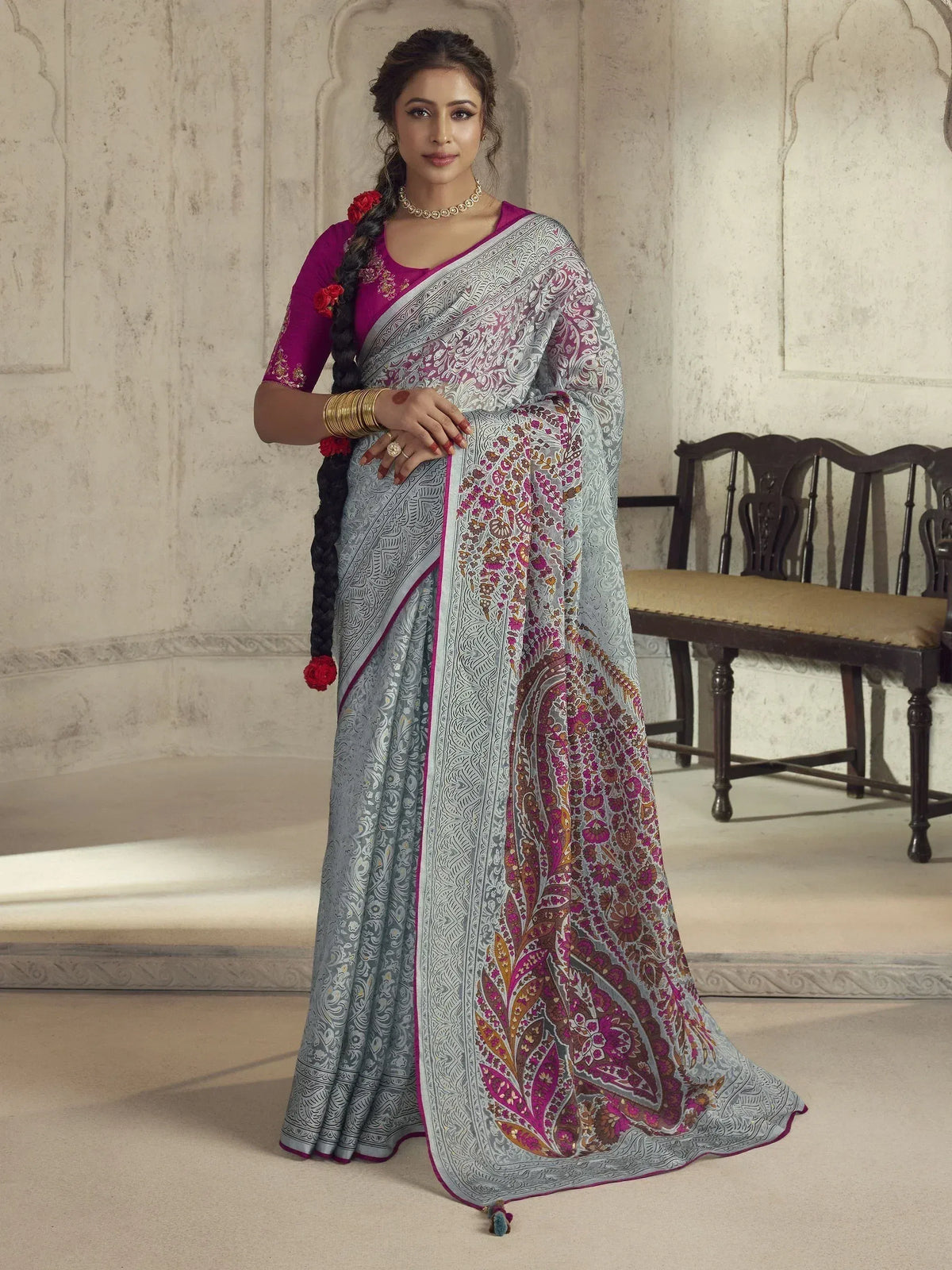 Woman in elegant grey and pink printed saree with floral motifs, paired with purple blouse, traditional Indian ethnic wear
