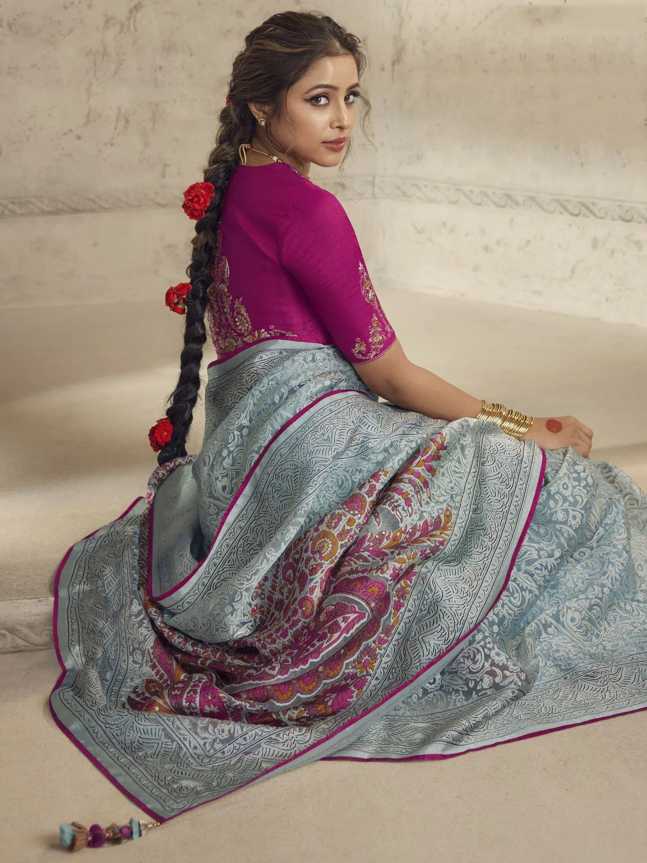 Woman in elegant blue paisley saree with magenta blouse, floral braid, gold jewelry, traditional Indian ethnic wear