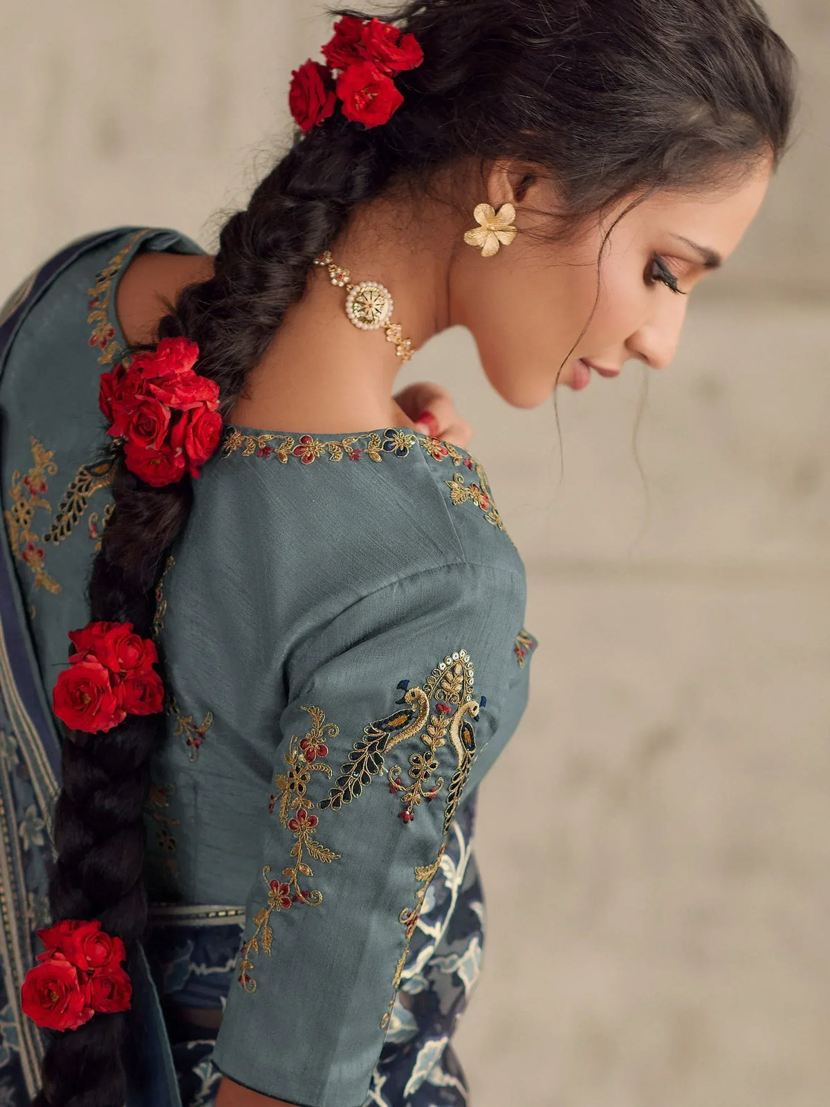Woman in teal embroidered ethnic wear with red rose hair accessories and gold jewelry