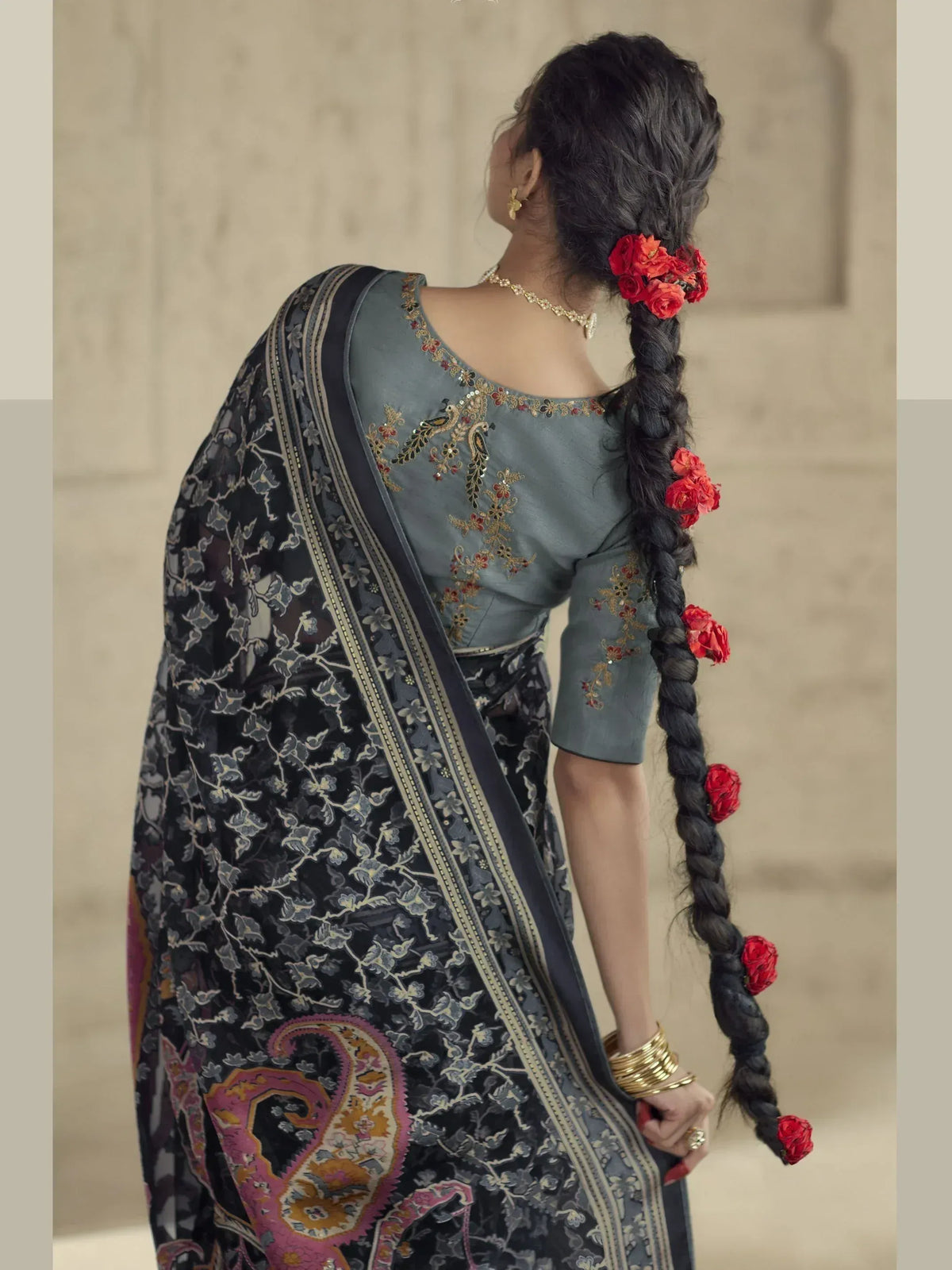 Woman in grey embroidered blouse with black floral saree, red rose hair accessories, gold jewelry