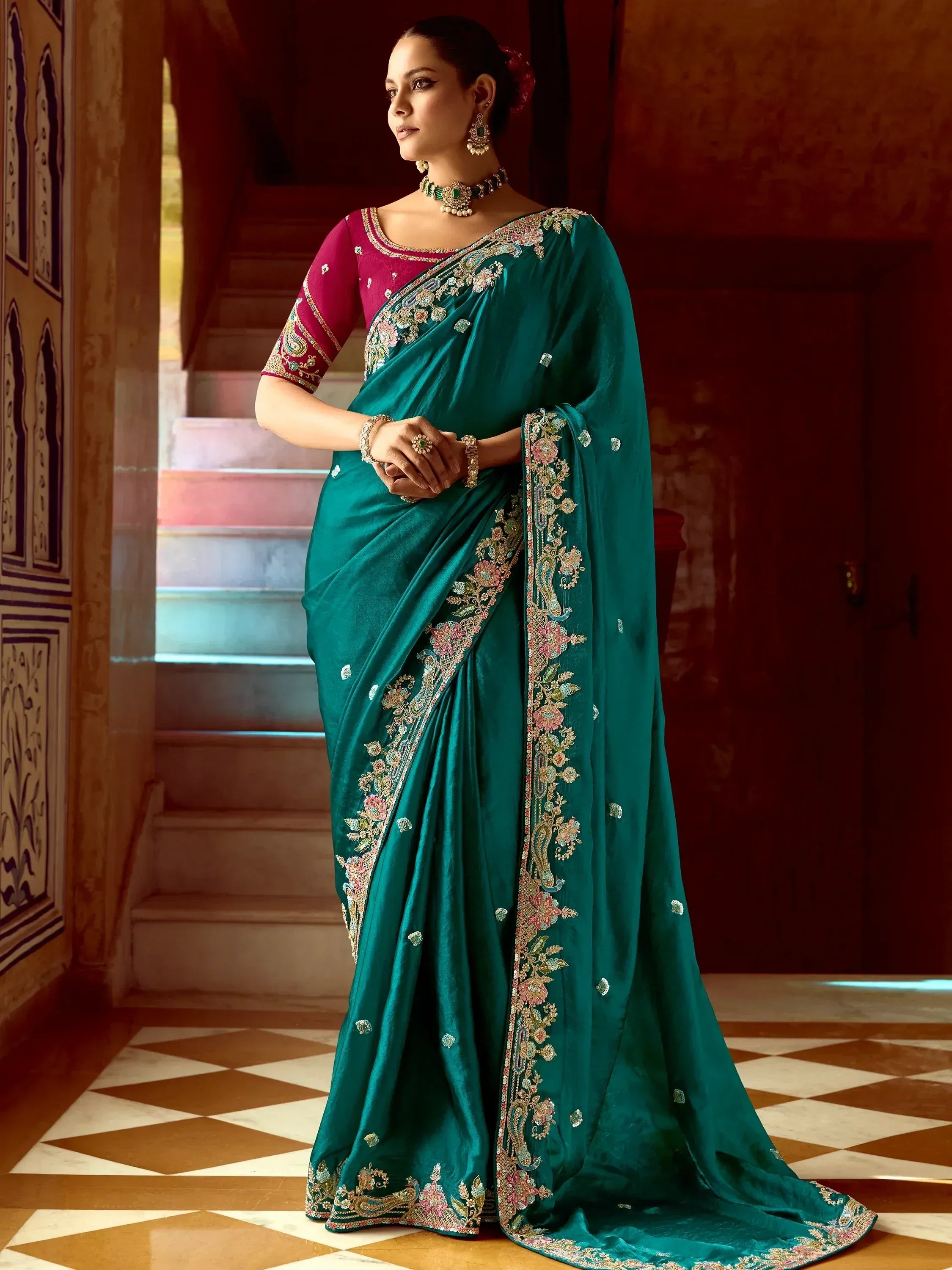 Emerald green embroidered saree with floral motifs and pink blouse, styled for ethnic occasions