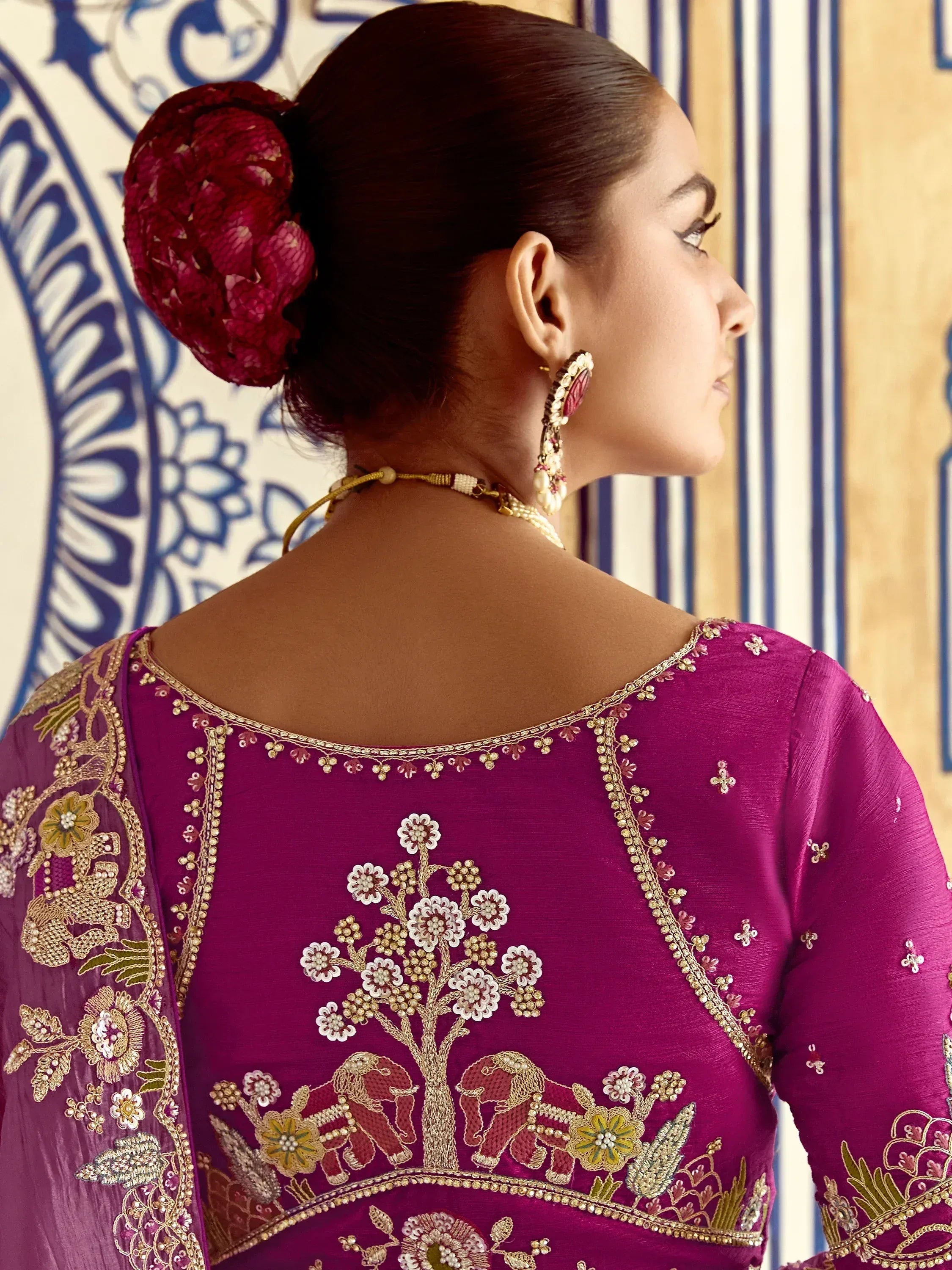 Purple embroidered ethnic blouse with floral and elephant motifs, paired with traditional jewelry