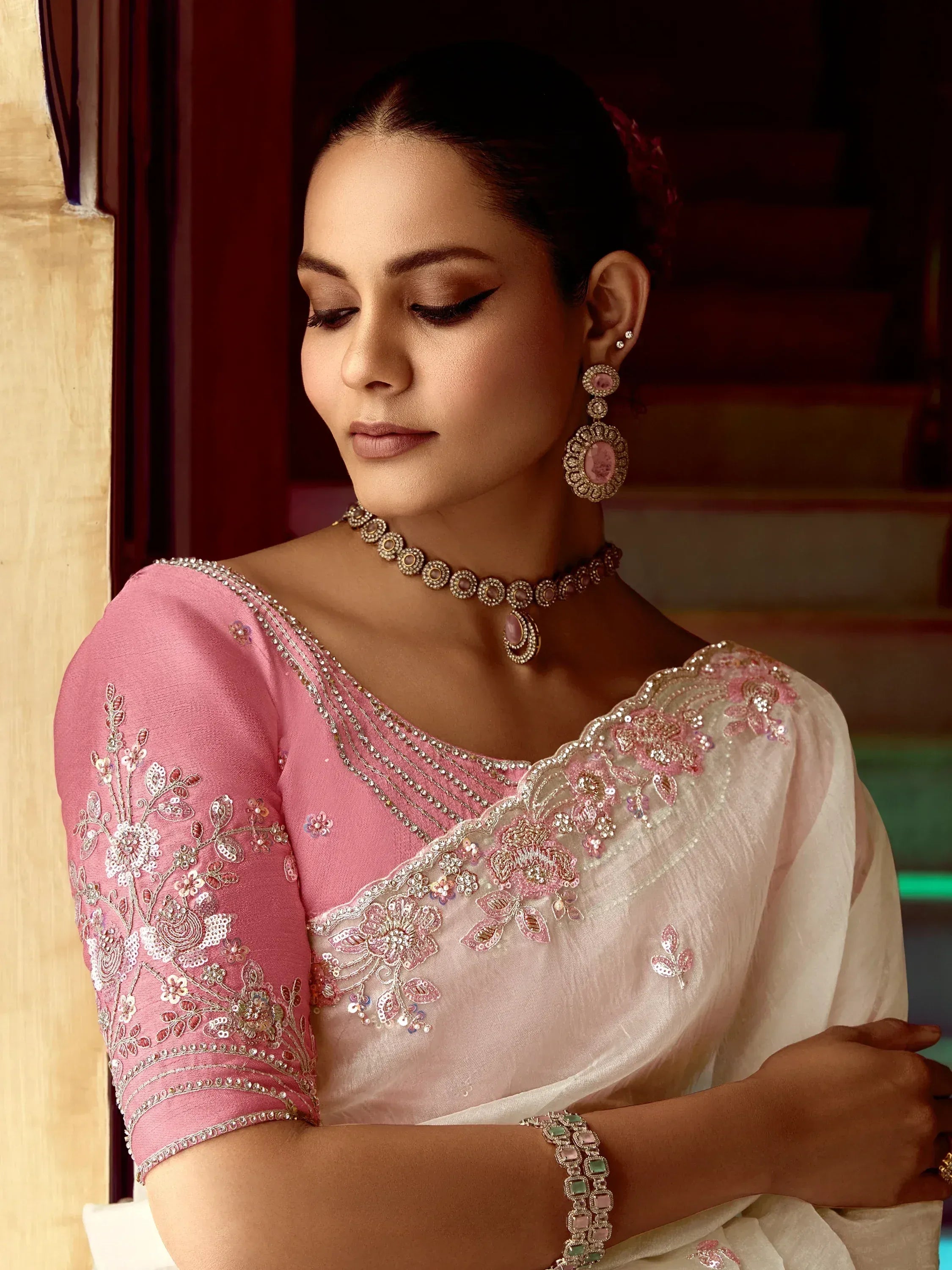 Elegant pink embroidered saree with floral detailing and matching jewelry for ethnic wear