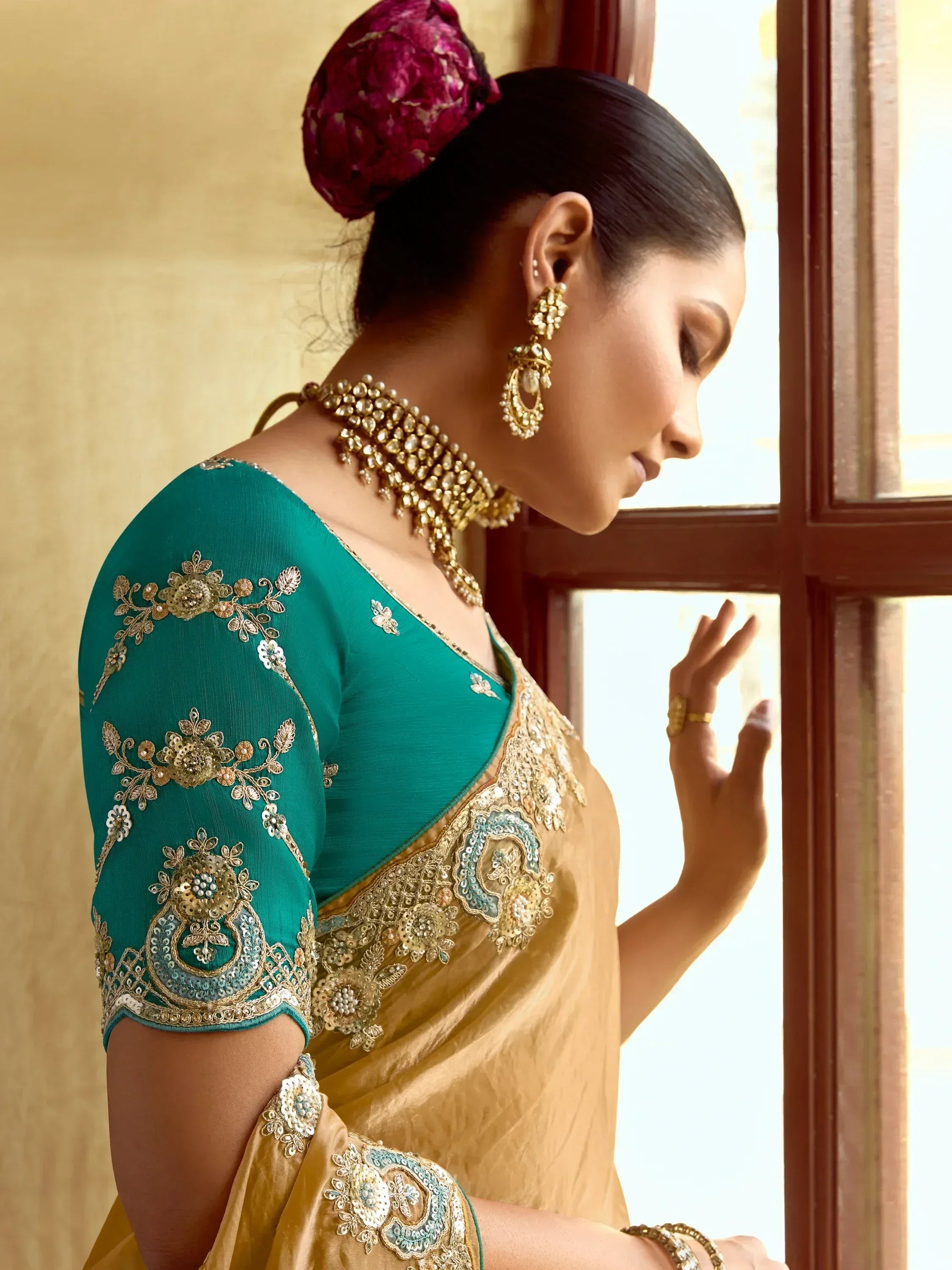 Elegant teal and gold embroidered saree with intricate floral designs and traditional jewelry