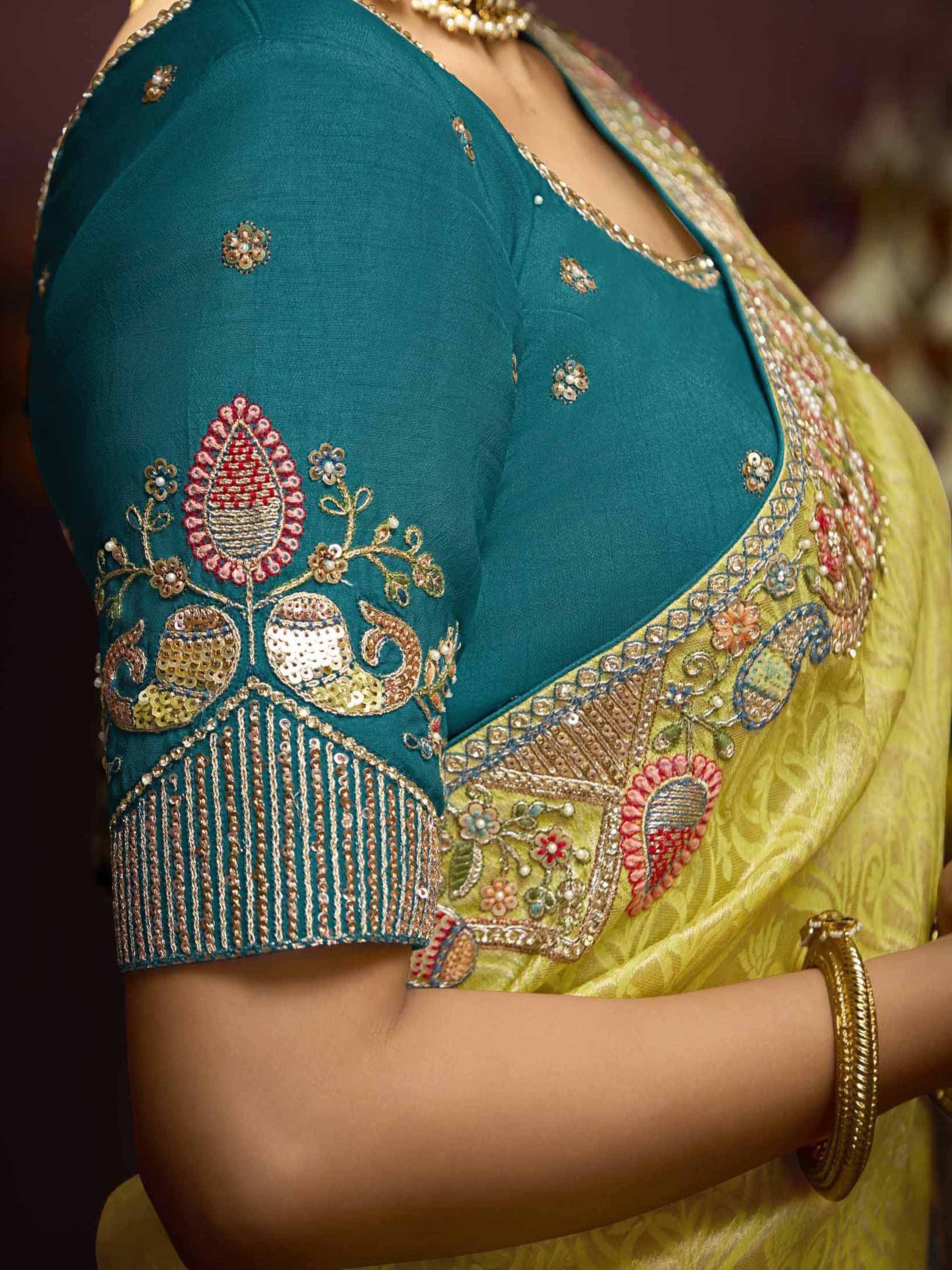 Teal embroidered blouse with gold sequin detailing paired with yellow saree, showcasing Indian ethnic wear design.