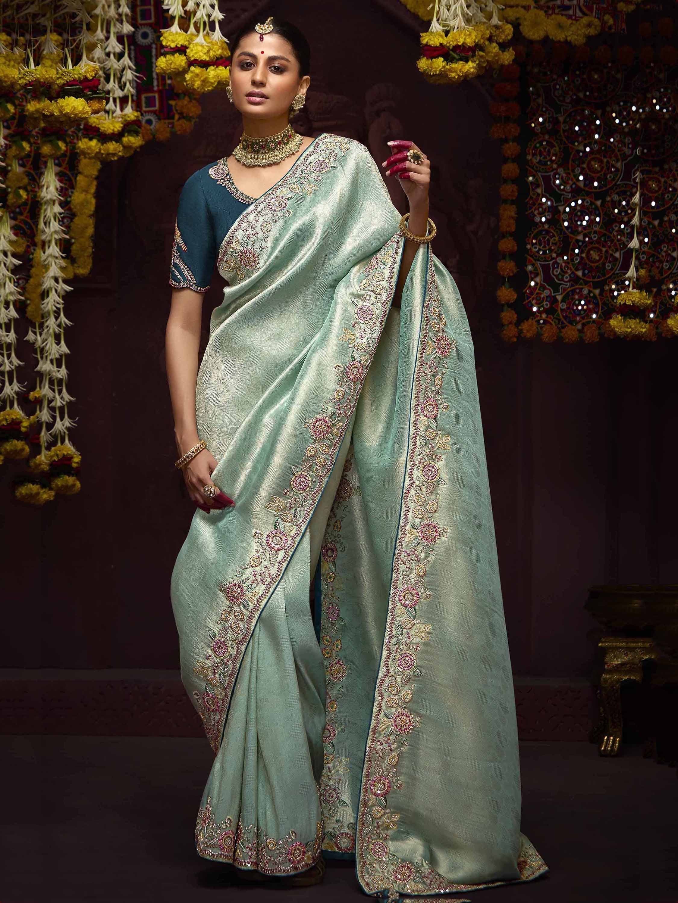 Mint green embroidered saree with floral border, paired with teal blouse, perfect for Indian ethnic occasions.