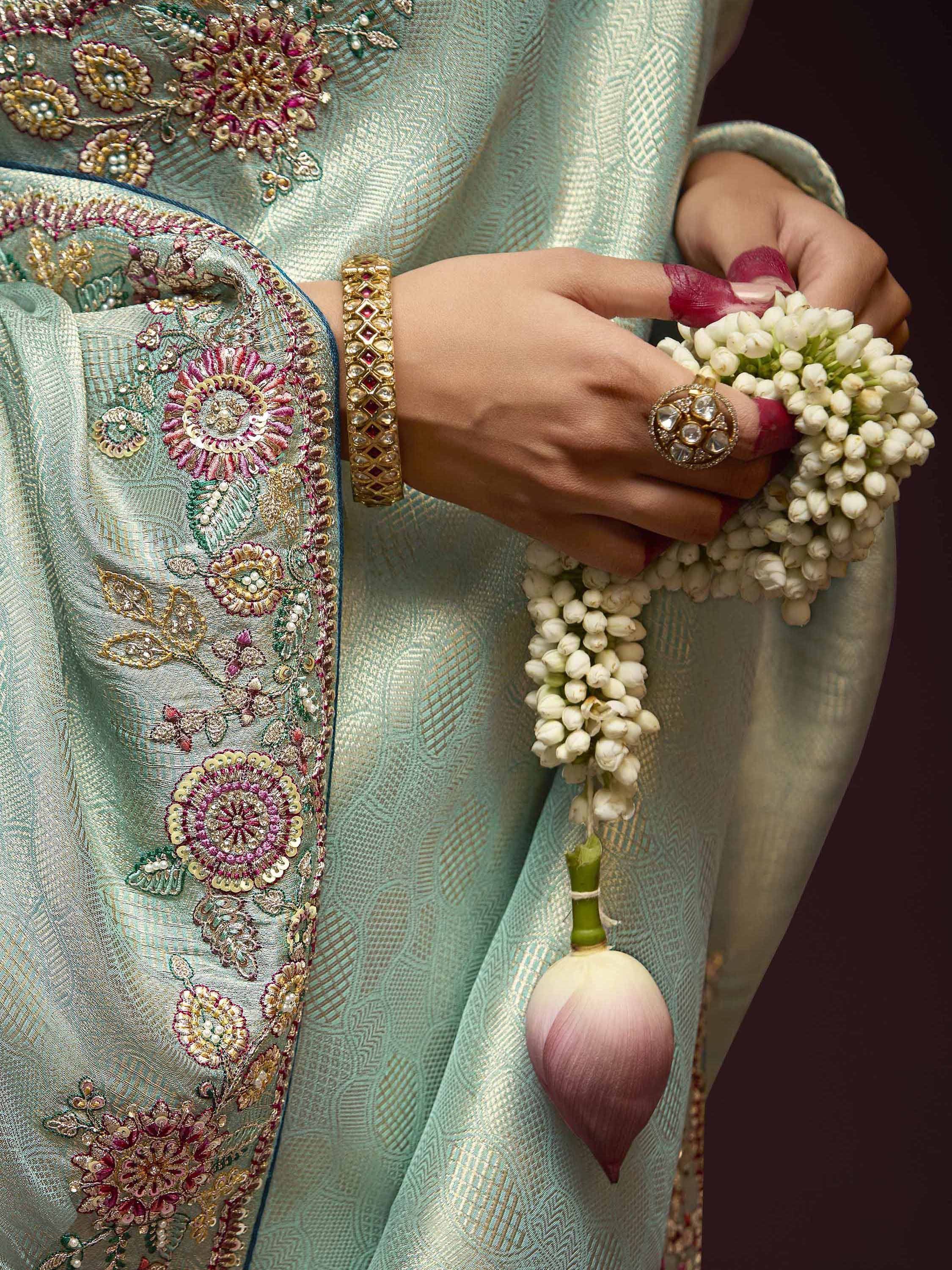 Elegant Indian ethnic wear with floral embroidery, gold jewelry, and jasmine garland for festive occasions