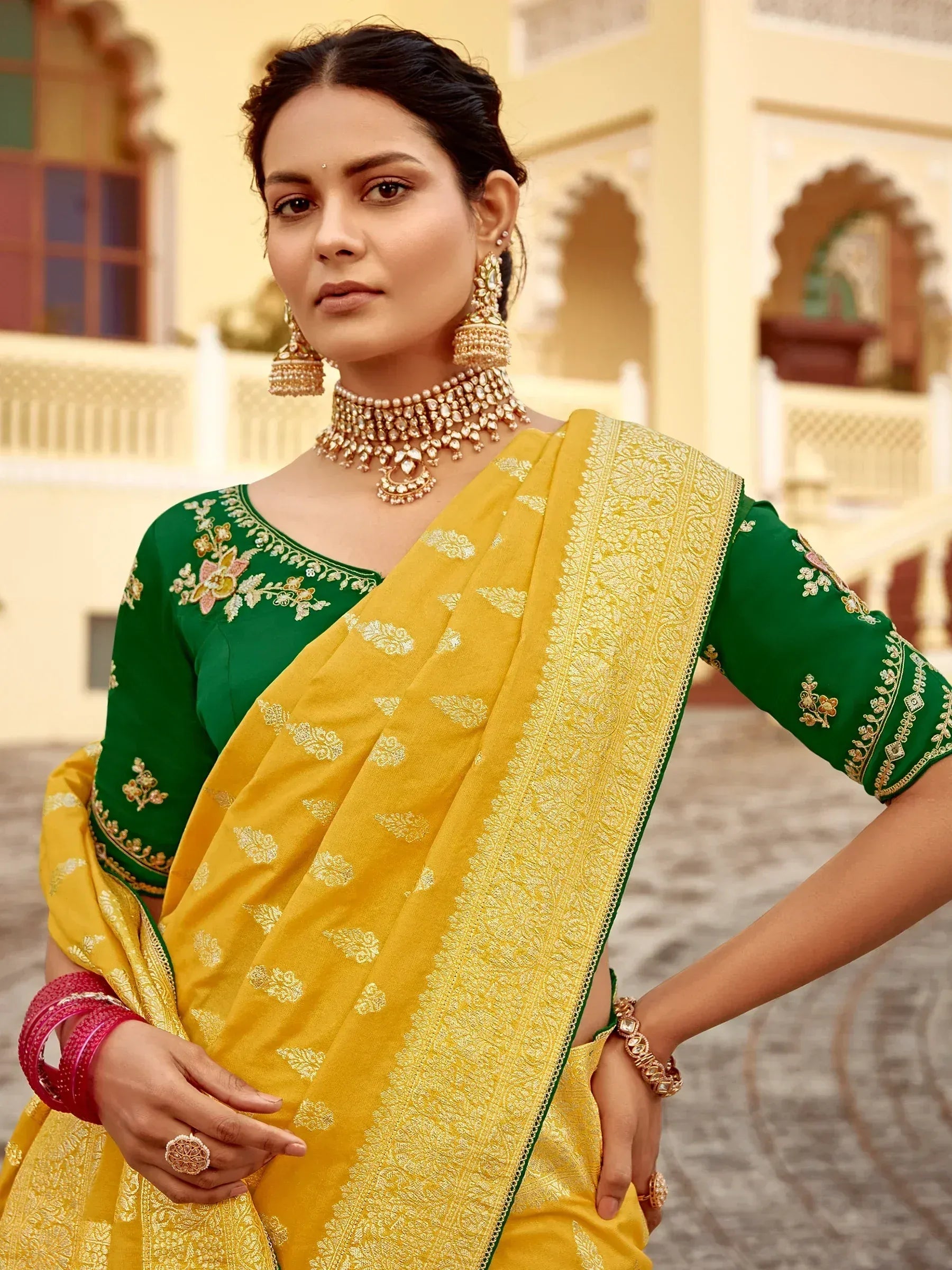 Woman in yellow and green embroidered saree with gold jewelry, traditional Indian ethnic wear