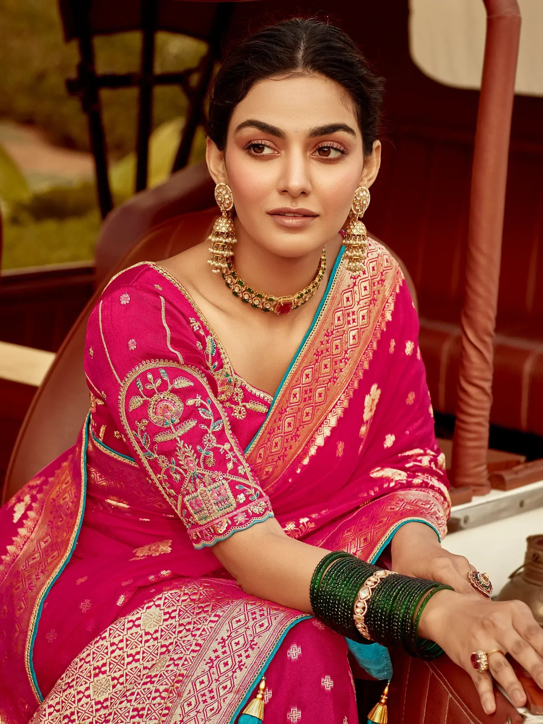 Woman in pink embroidered saree with gold jewelry, traditional Indian ethnic wear