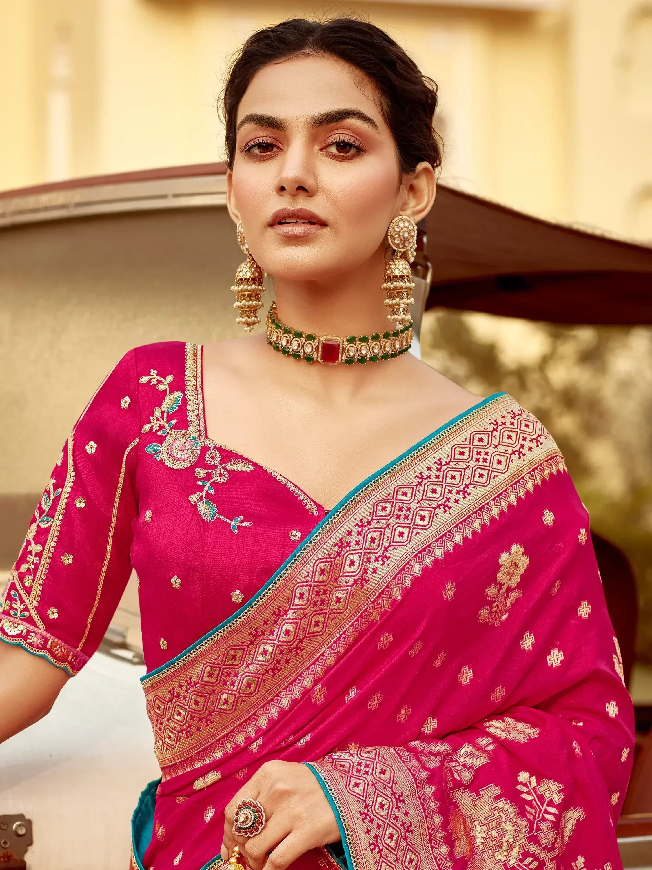 Pink embroidered saree with gold border, floral blouse, and traditional jewelry for Indian ethnic wear