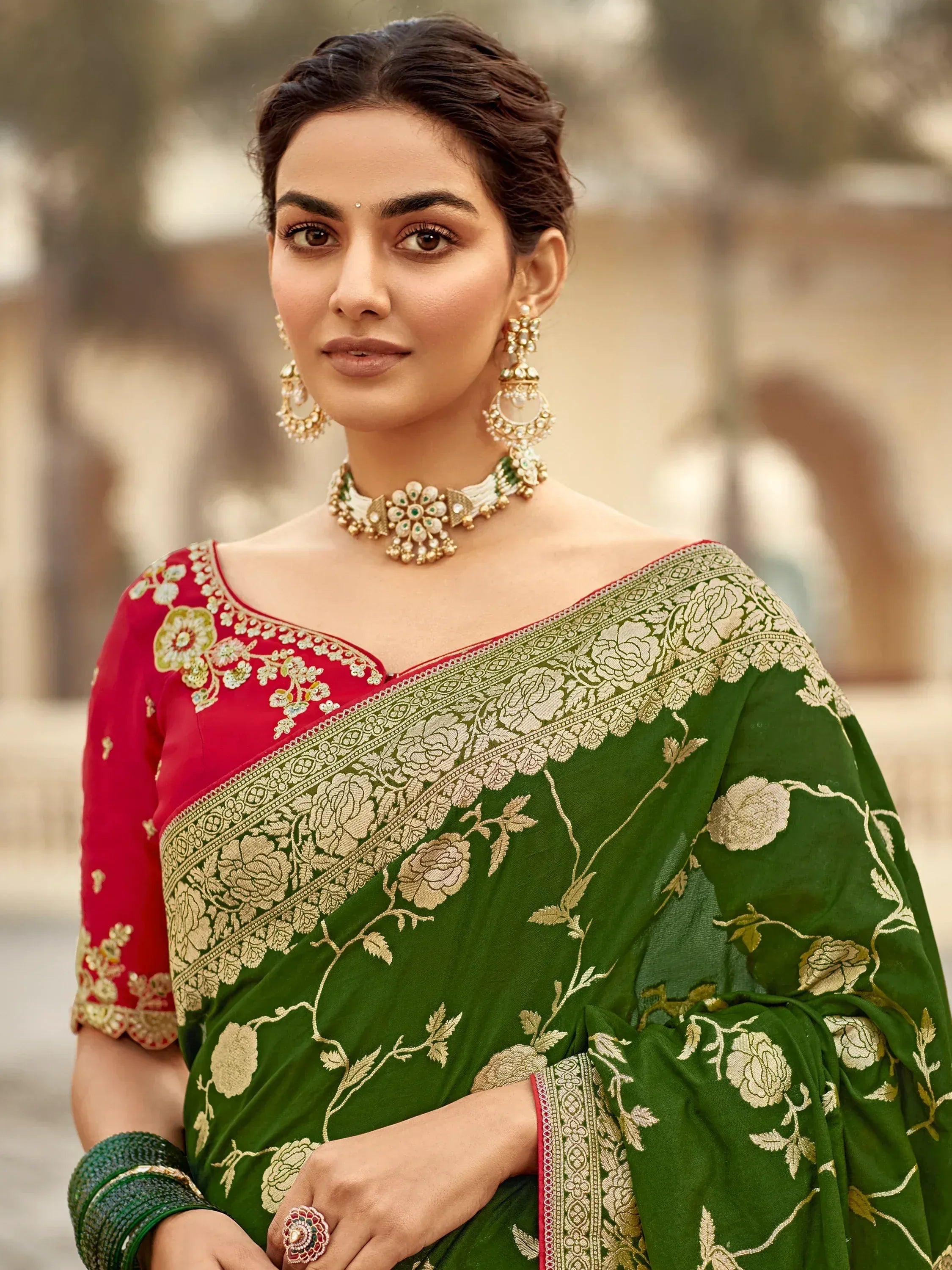 Green floral saree with red blouse, gold embroidery, and traditional Indian jewelry