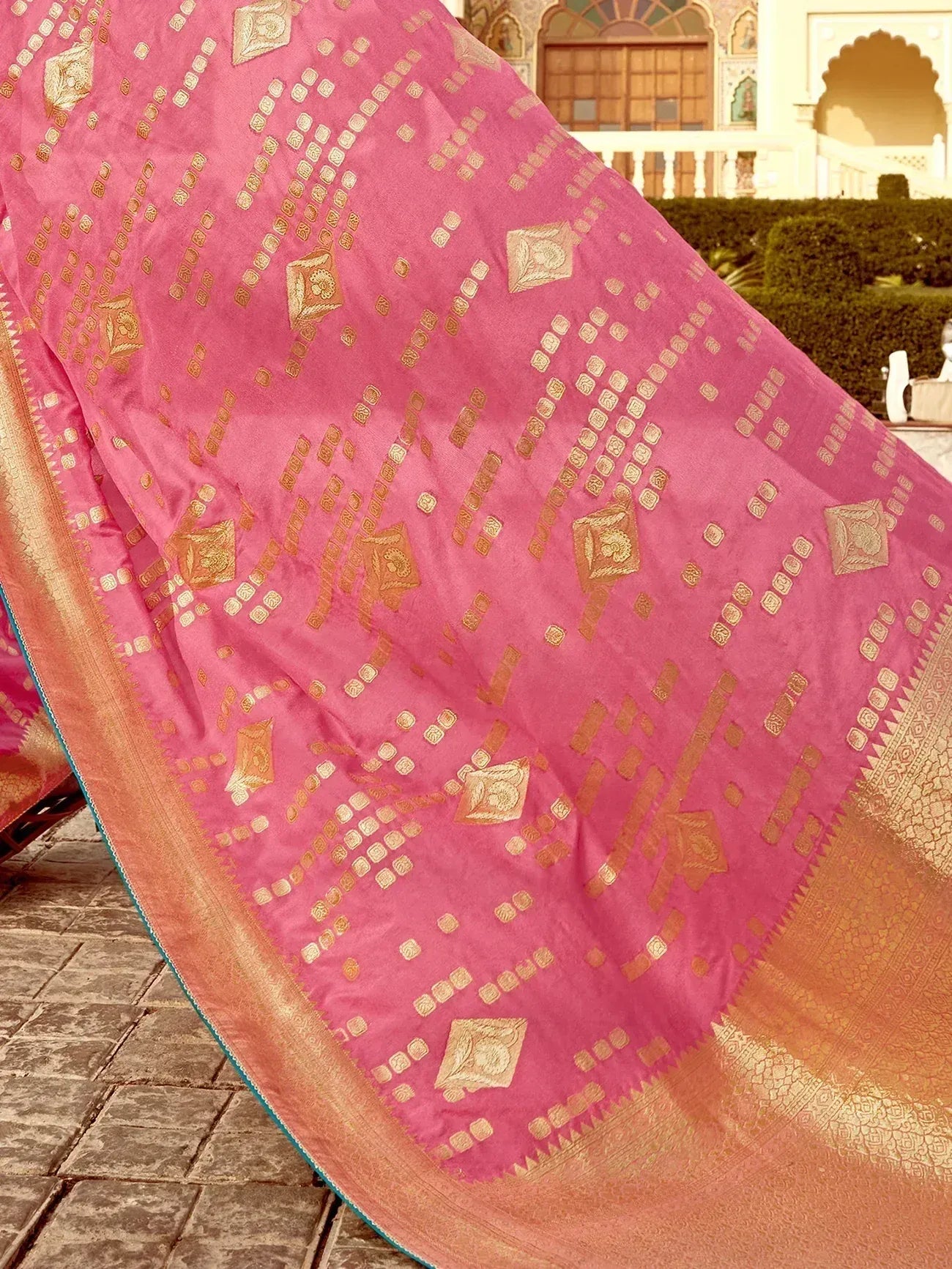 Pink designer saree with gold geometric patterns and ornate border, ideal for ethnic occasions