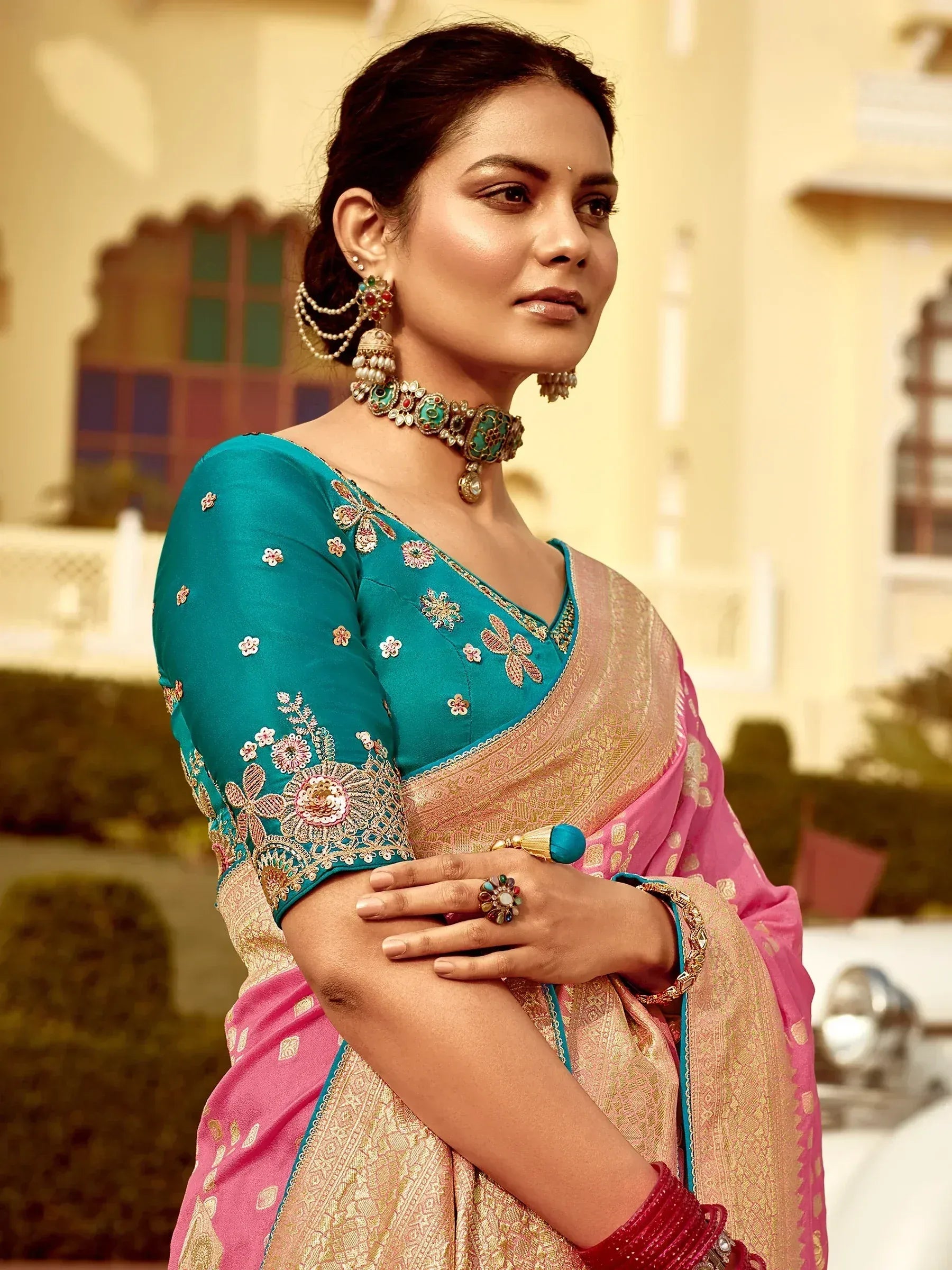 Elegant woman in turquoise and pink embroidered saree with traditional jewelry