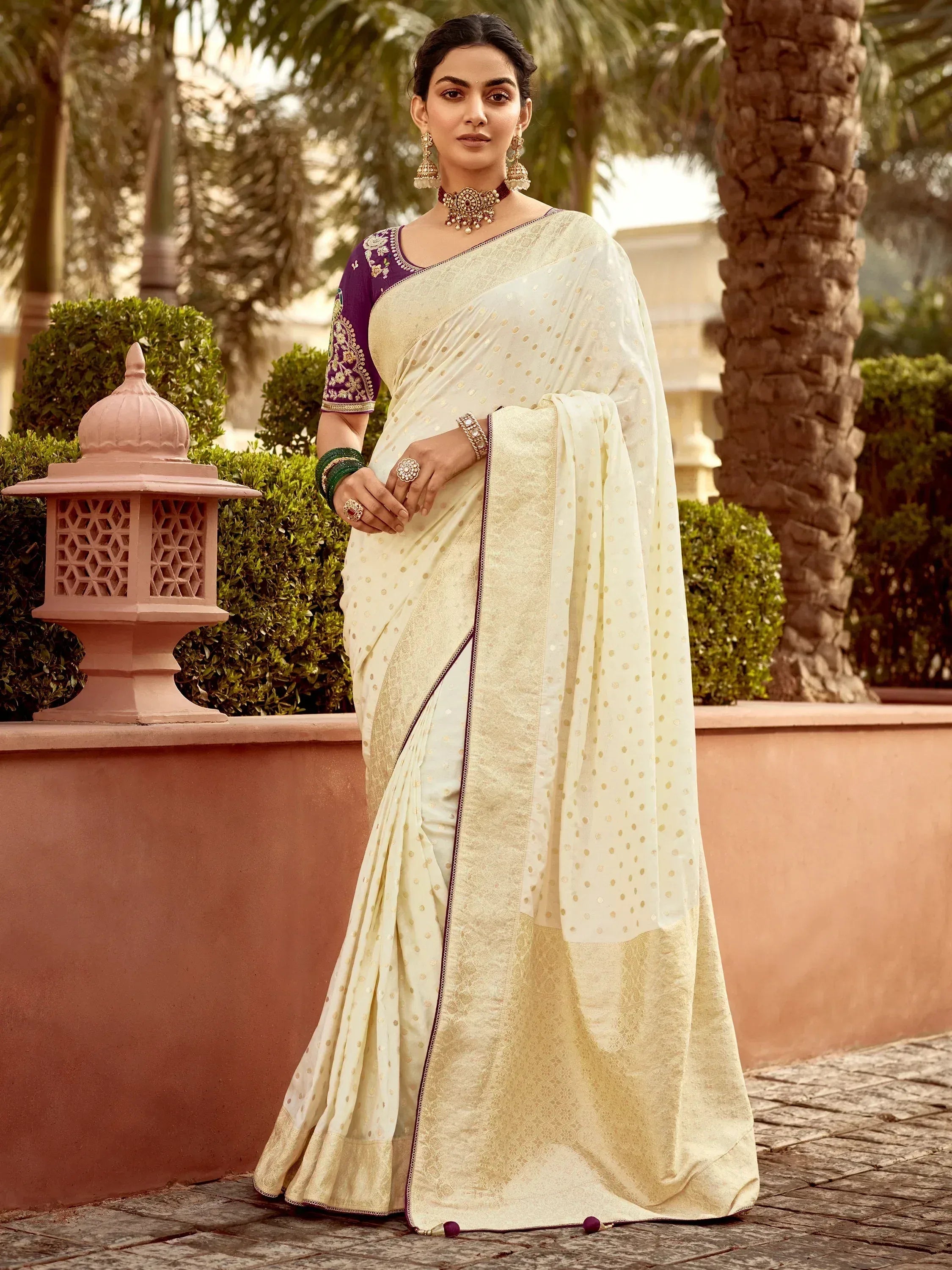 Elegant cream saree with gold polka dots and purple embroidered blouse, perfect for Indian ethnic occasions.
