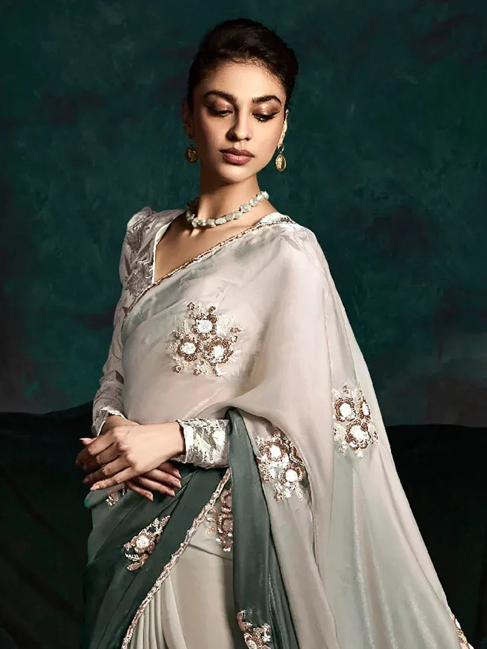 Elegant off-white saree with gold floral embroidery and green border, styled with pearl jewelry for Indian ethnic wear