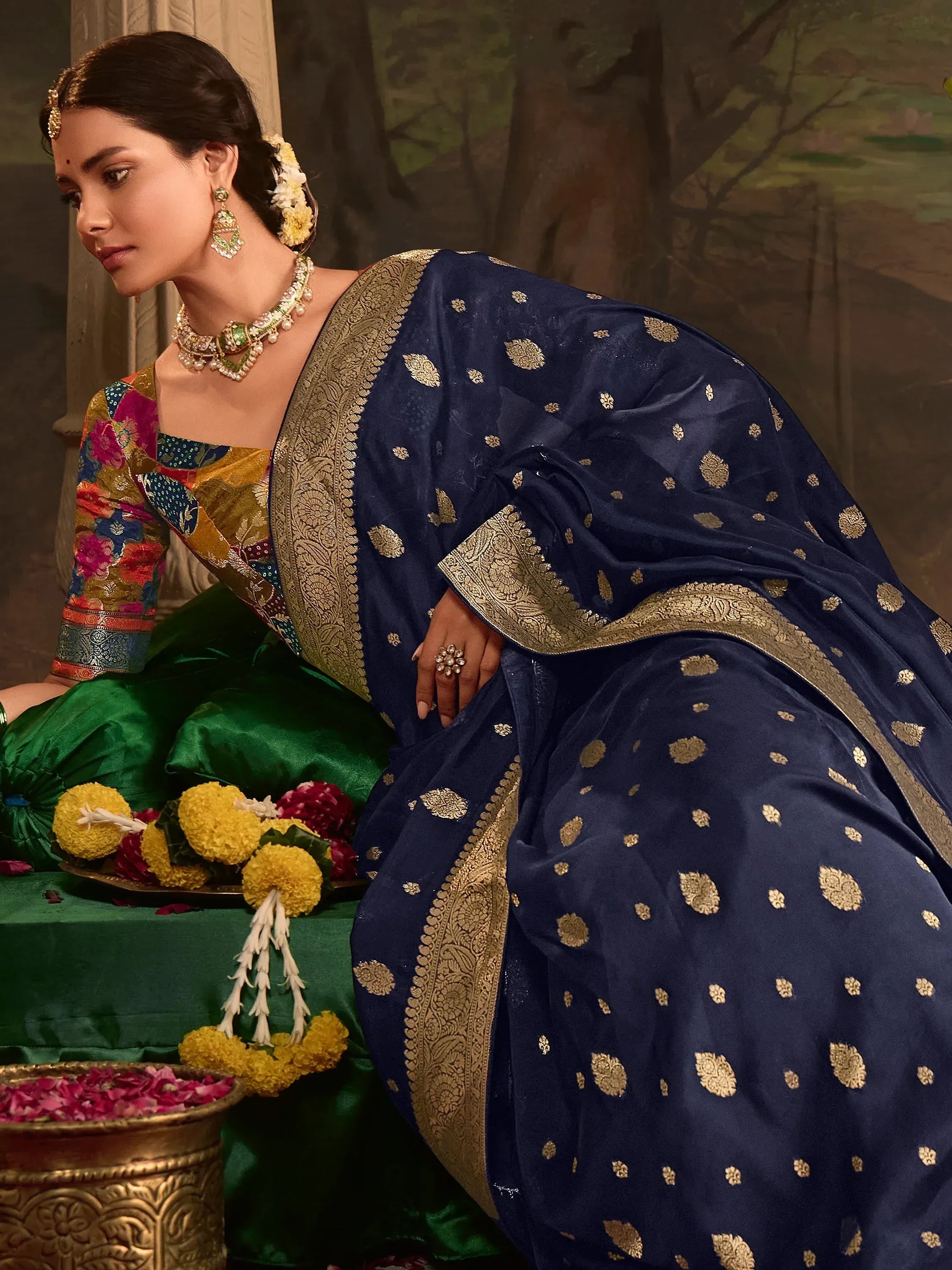 Navy blue saree with gold floral motifs and embroidered border, paired with colorful blouse and traditional jewelry