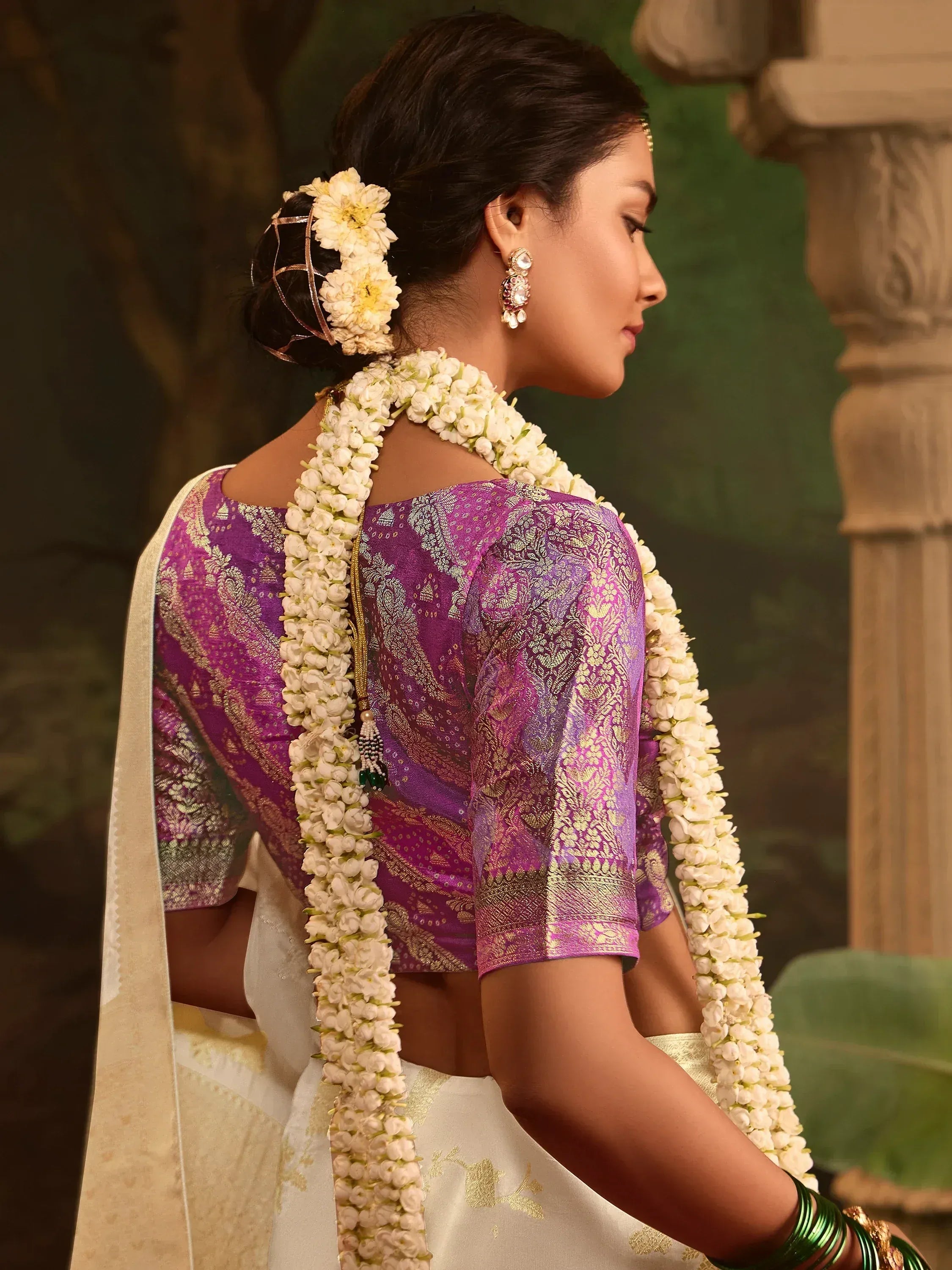 Woman in purple and gold designer saree blouse with floral garland, traditional Indian ethnic wear