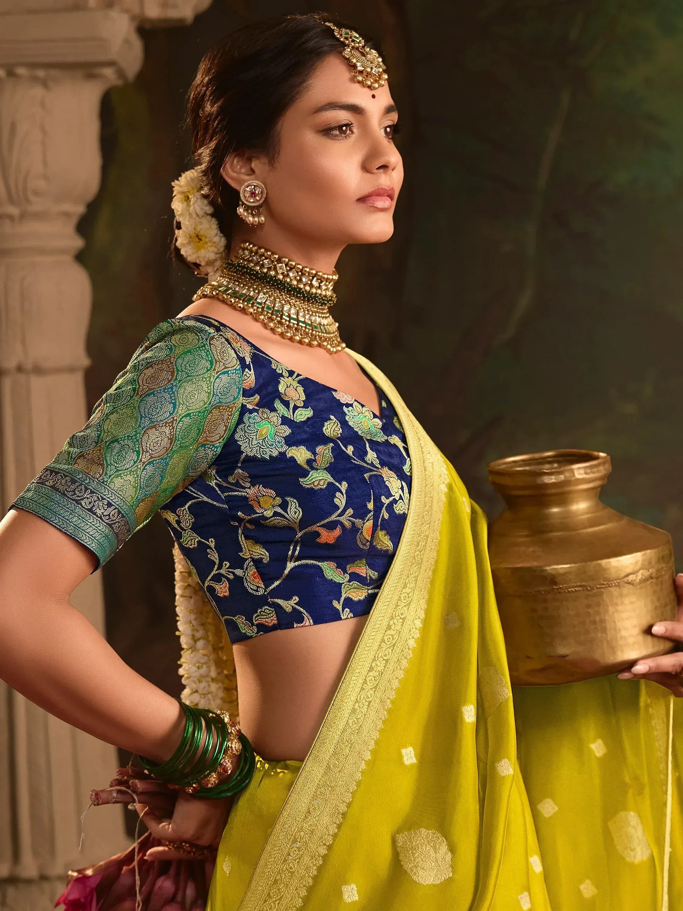 Elegant woman in blue floral blouse and yellow saree with traditional jewelry