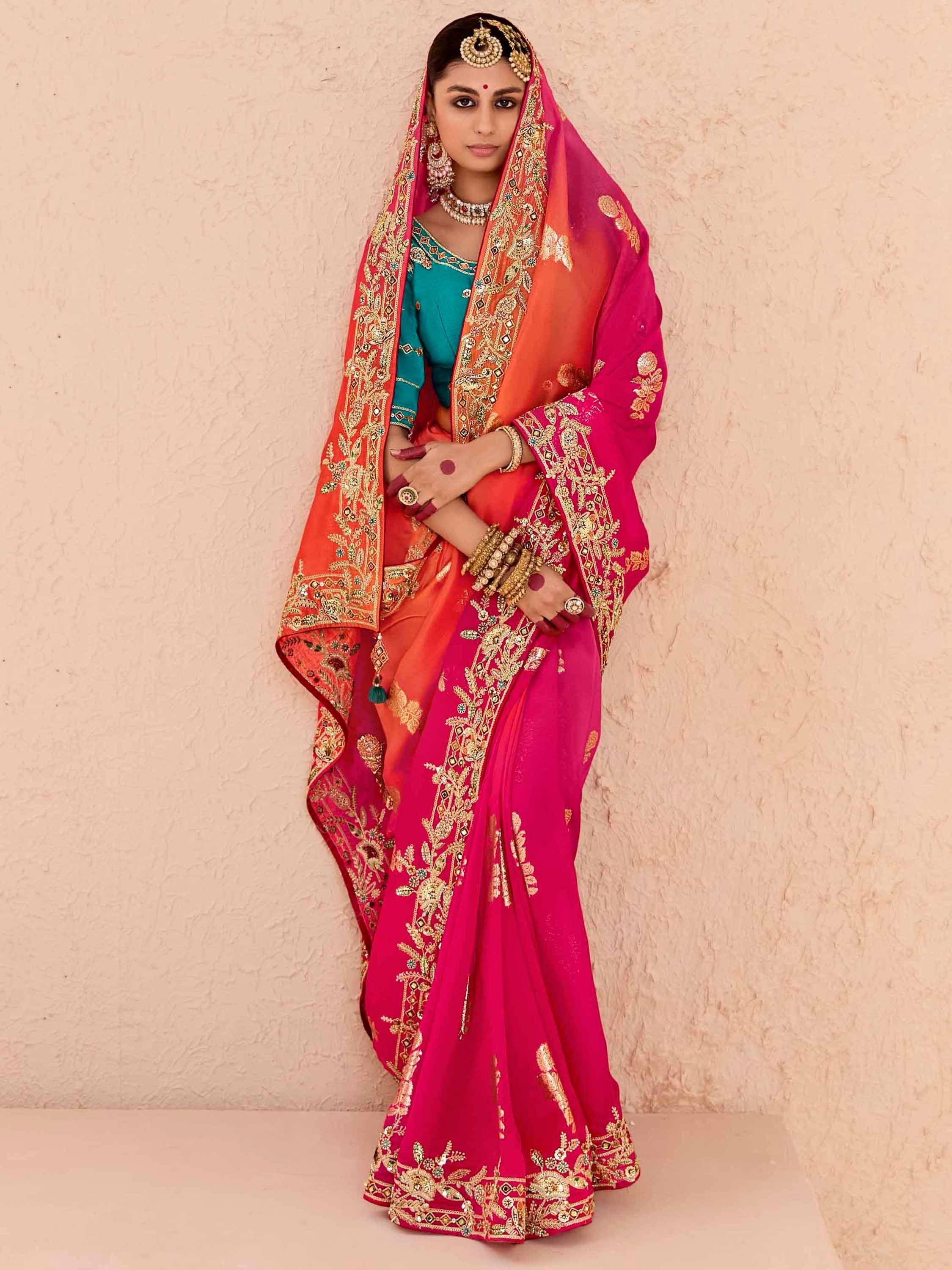 Pink and orange embroidered saree with gold detailing, paired with teal blouse and traditional jewelry