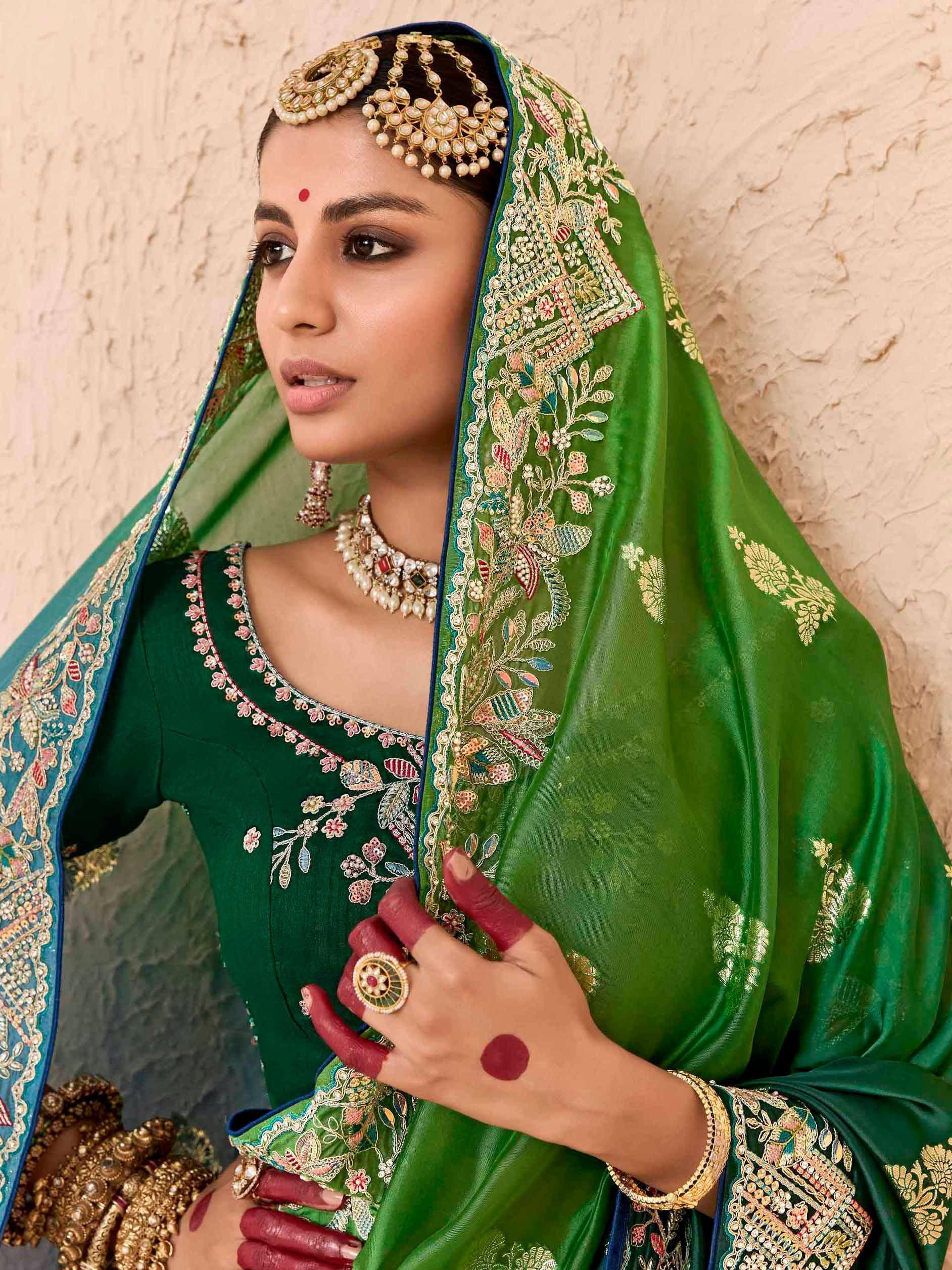 Green embroidered Indian bridal lehenga choli with matching dupatta and traditional jewelry