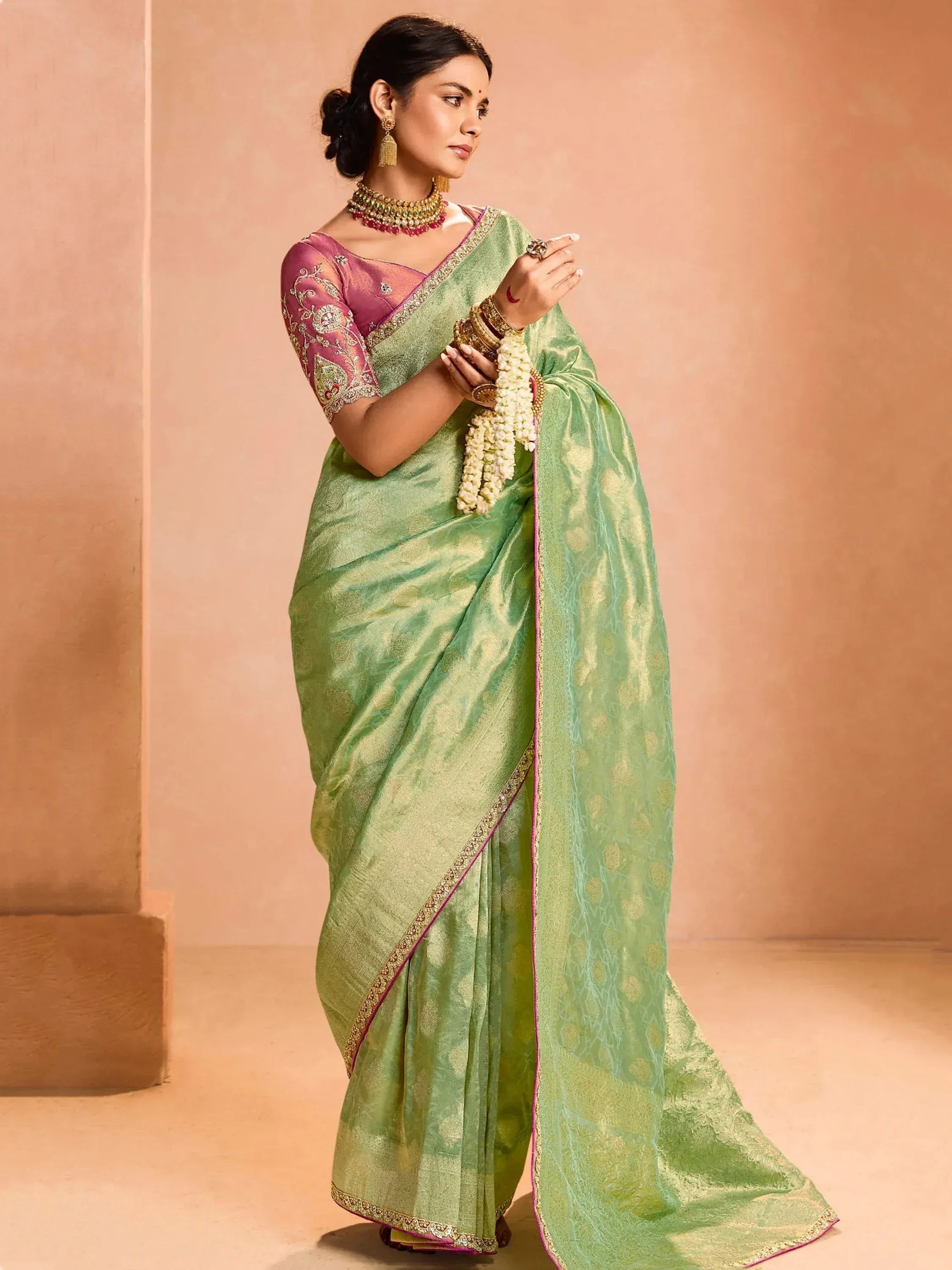 Green silk saree with pink blouse, gold embroidery, and traditional jewelry for Indian ethnic wear