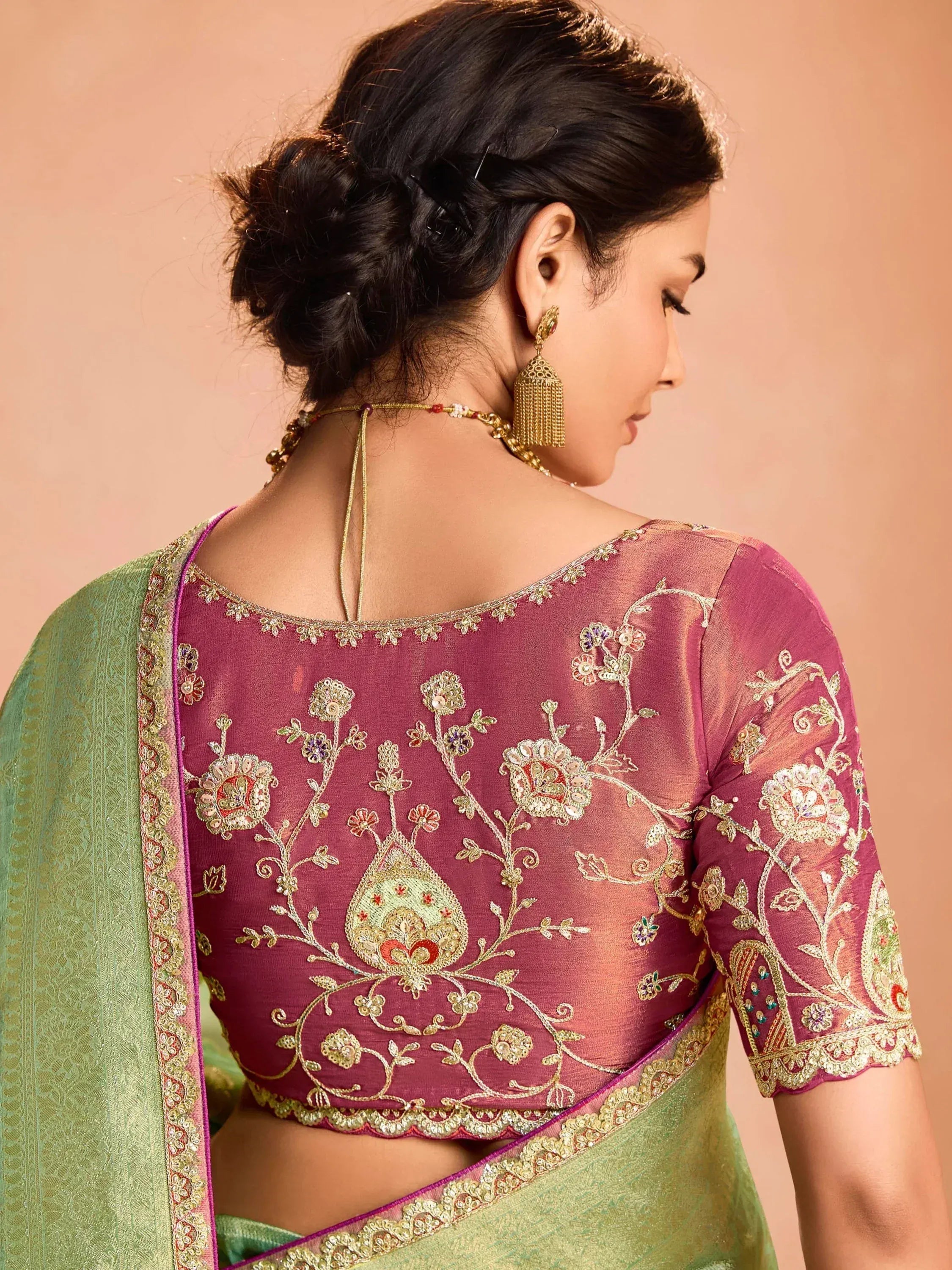 Woman in maroon embroidered blouse with green saree, floral zari work, perfect for Indian ethnic wear occasions.