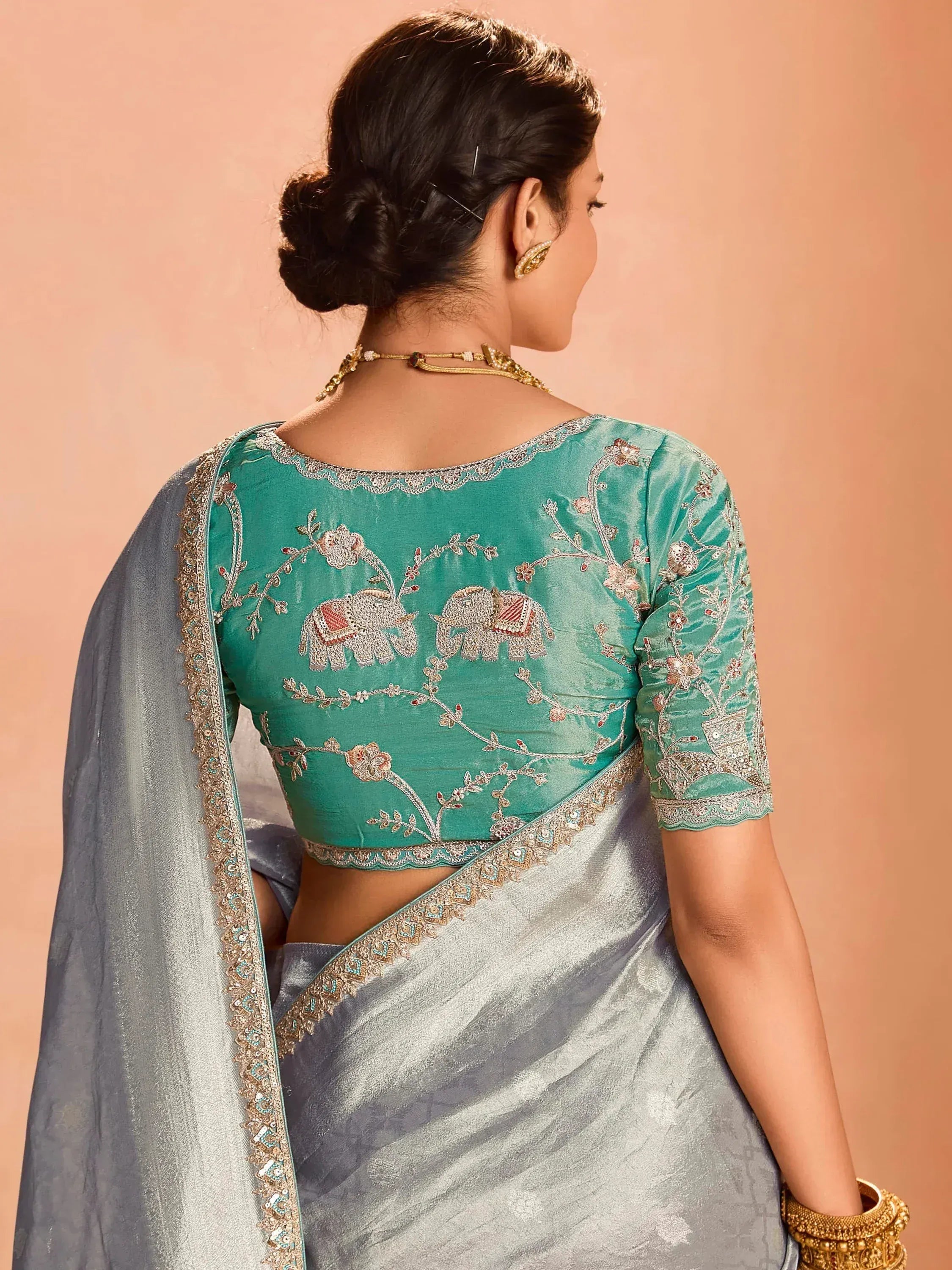 Teal embroidered blouse with elephant motifs paired with silver saree, ideal for Indian ethnic wear