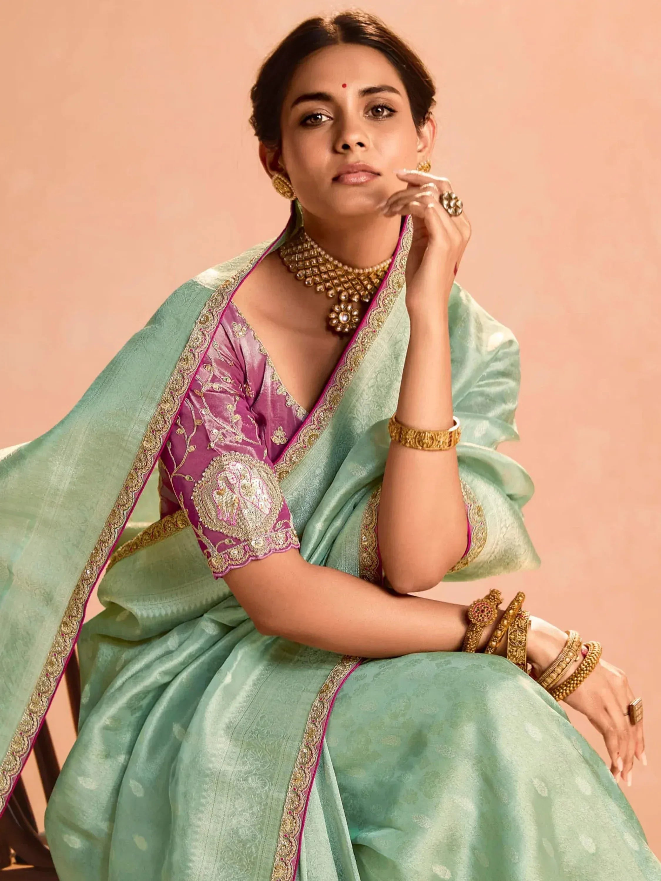Elegant woman in mint green saree with pink blouse, gold embroidery, and traditional jewelry for Indian ethnic wear