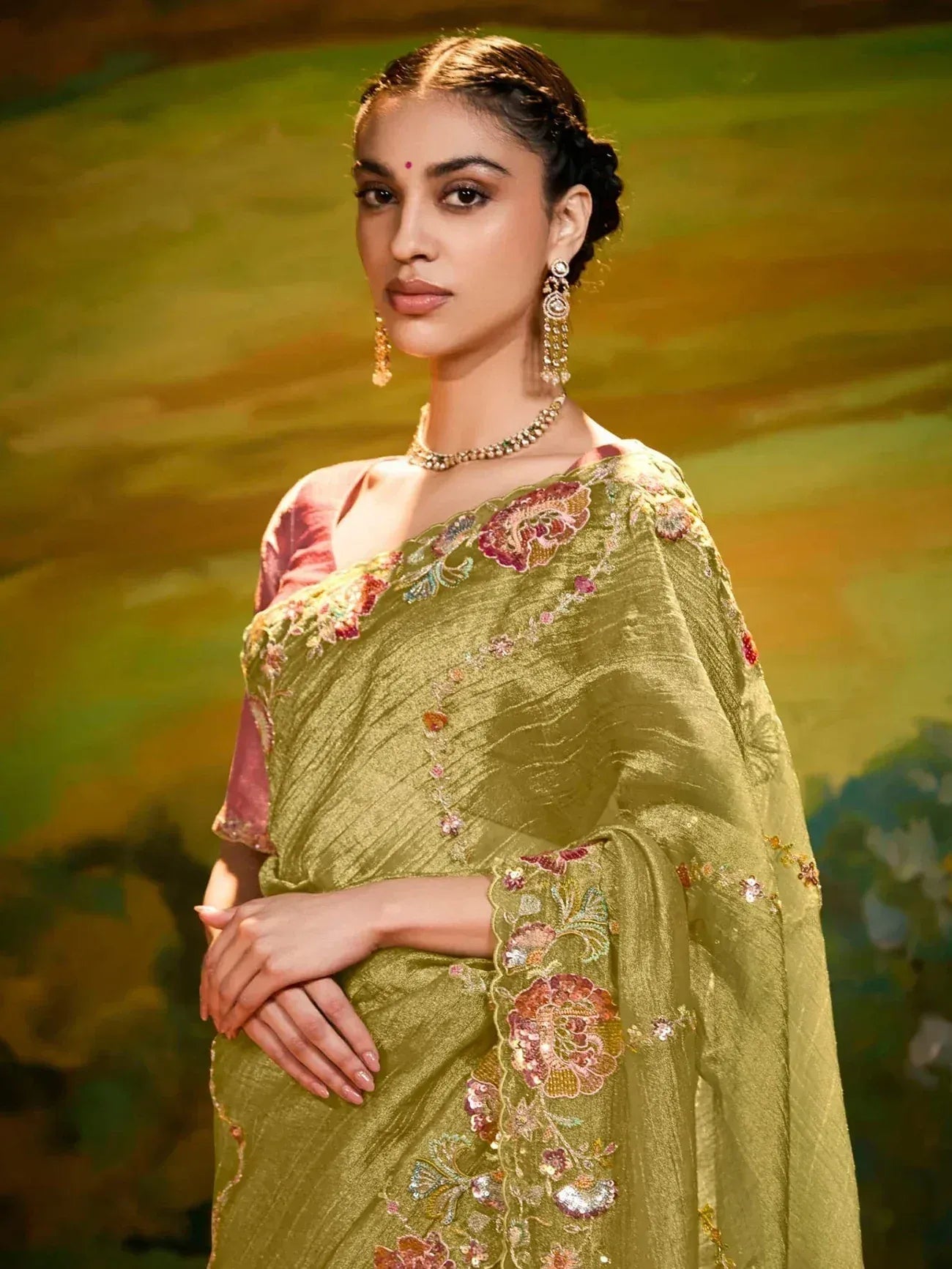 Olive green embroidered saree with floral motifs, paired with pink blouse and traditional jewelry