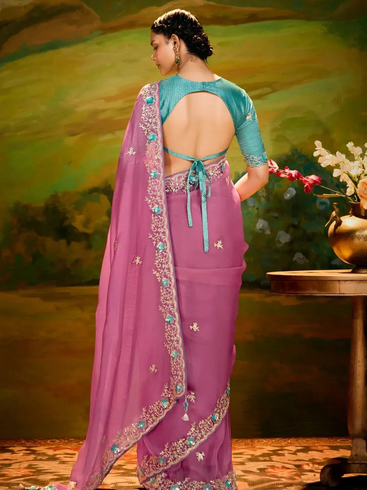 Woman in golden yellow saree with pink border and floral motifs, paired with pink blouse, styled for ethnic occasions