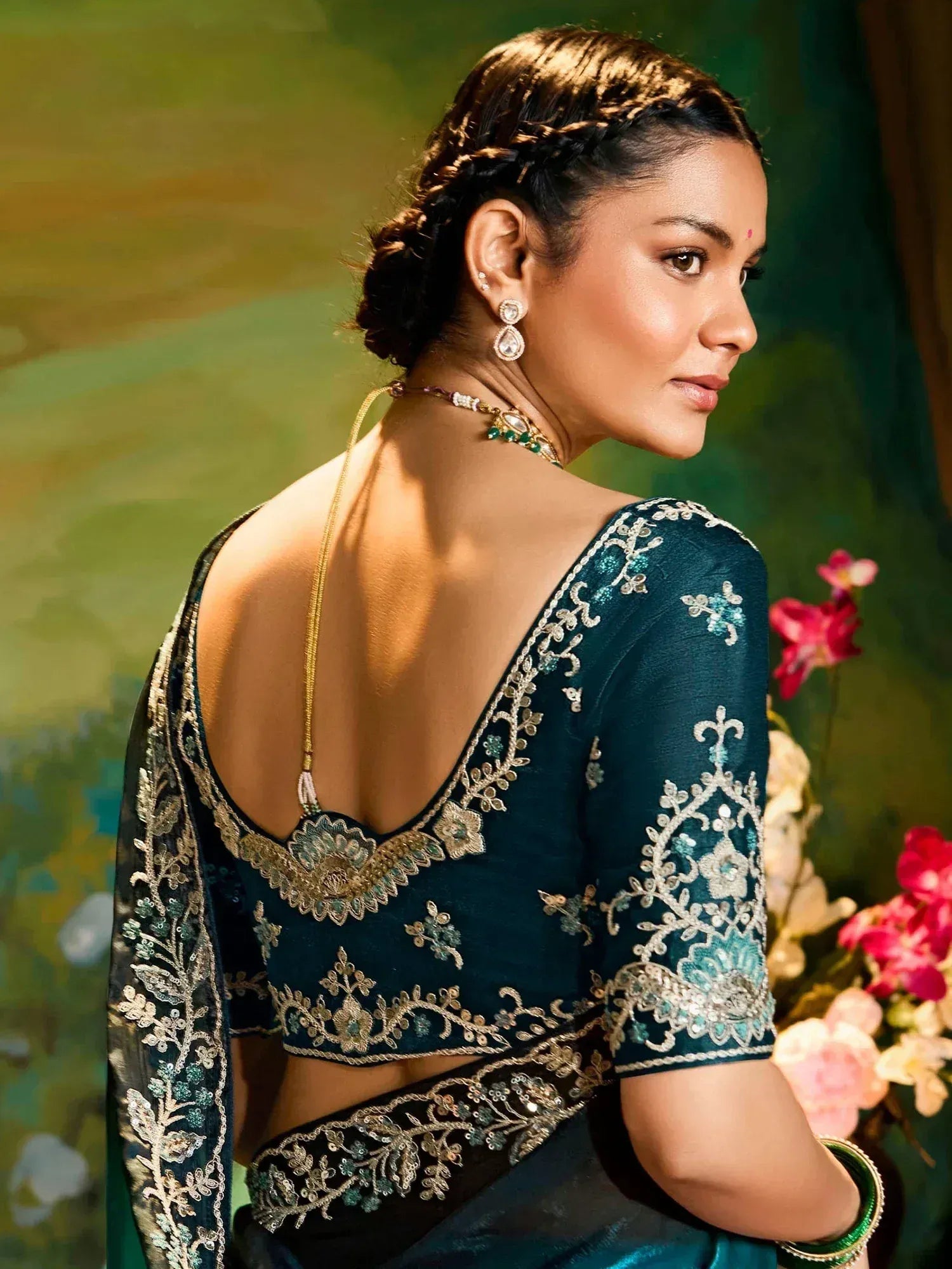 Elegant teal saree blouse with gold embroidery, backless design, and traditional Indian jewelry