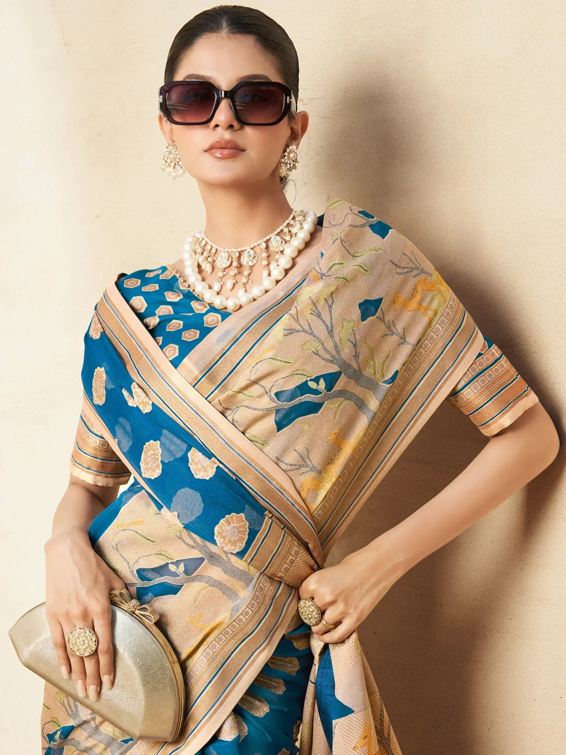 Woman in blue and beige printed saree with pearl jewelry and sunglasses, elegant ethnic wear