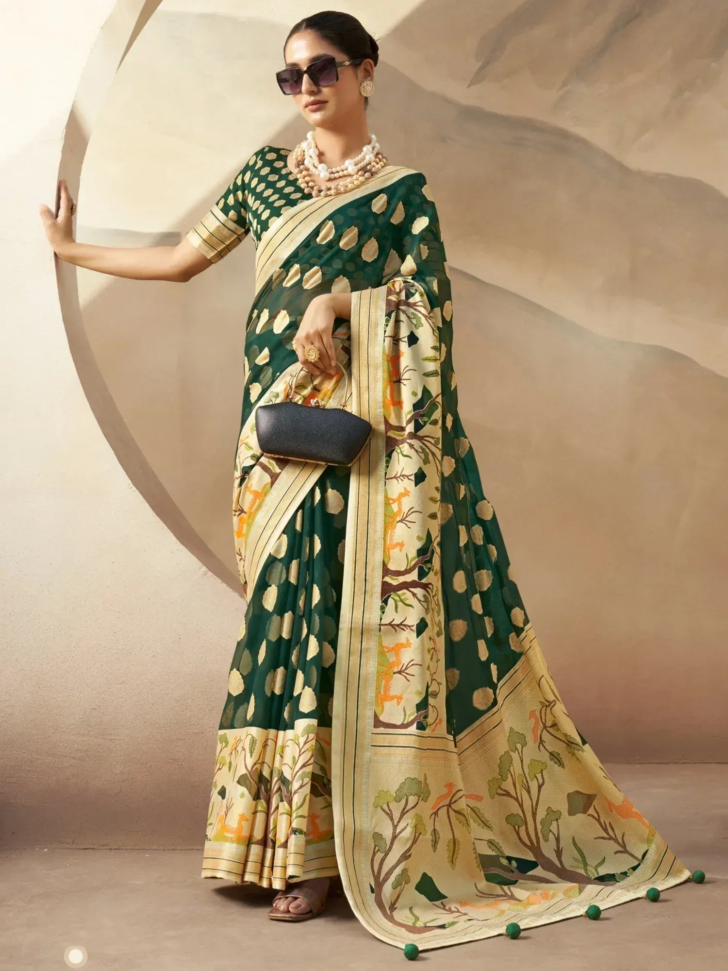 Woman in green and cream printed saree with nature motifs, styled with pearl necklace and sunglasses