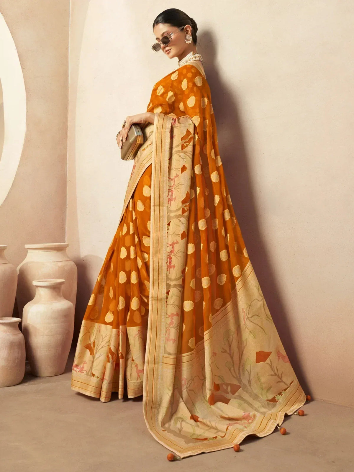 Woman in orange printed saree with floral border, ethnic Indian wear for festive occasions