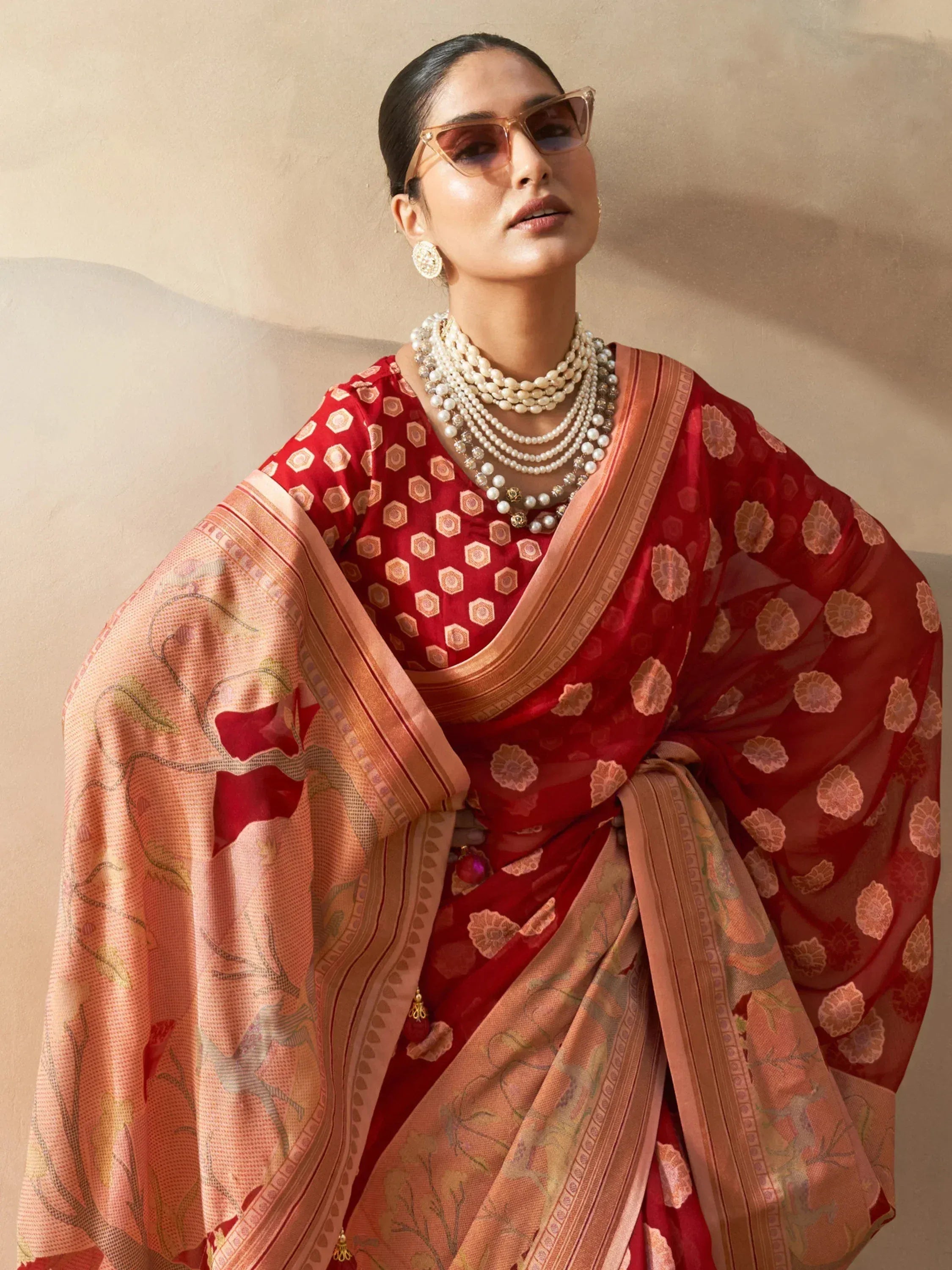 Woman in red and peach printed saree with pearl jewelry, stylish ethnic wear for festive occasions