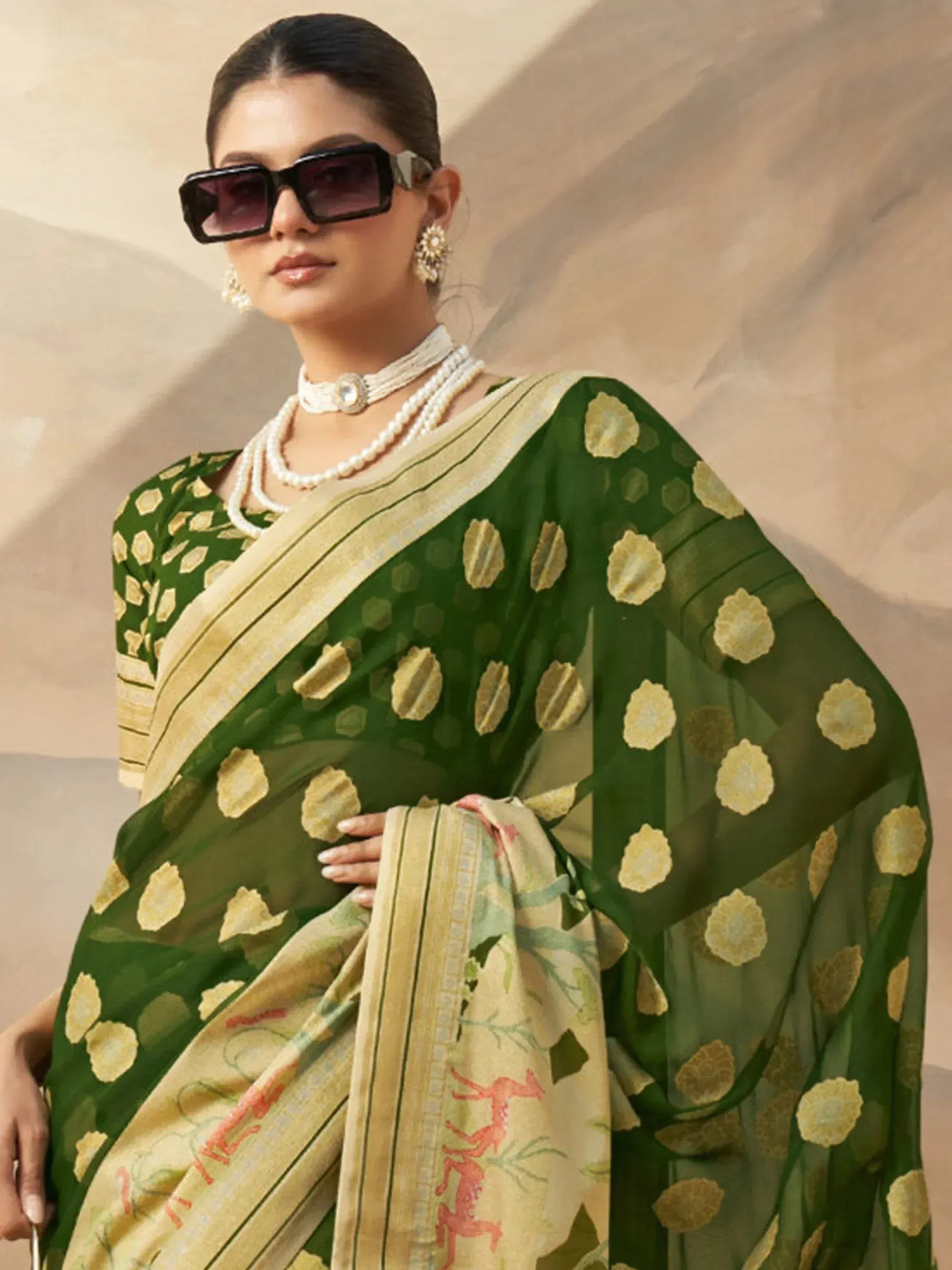 Green floral printed saree with gold motifs and deer design, paired with pearl jewelry and sunglasses