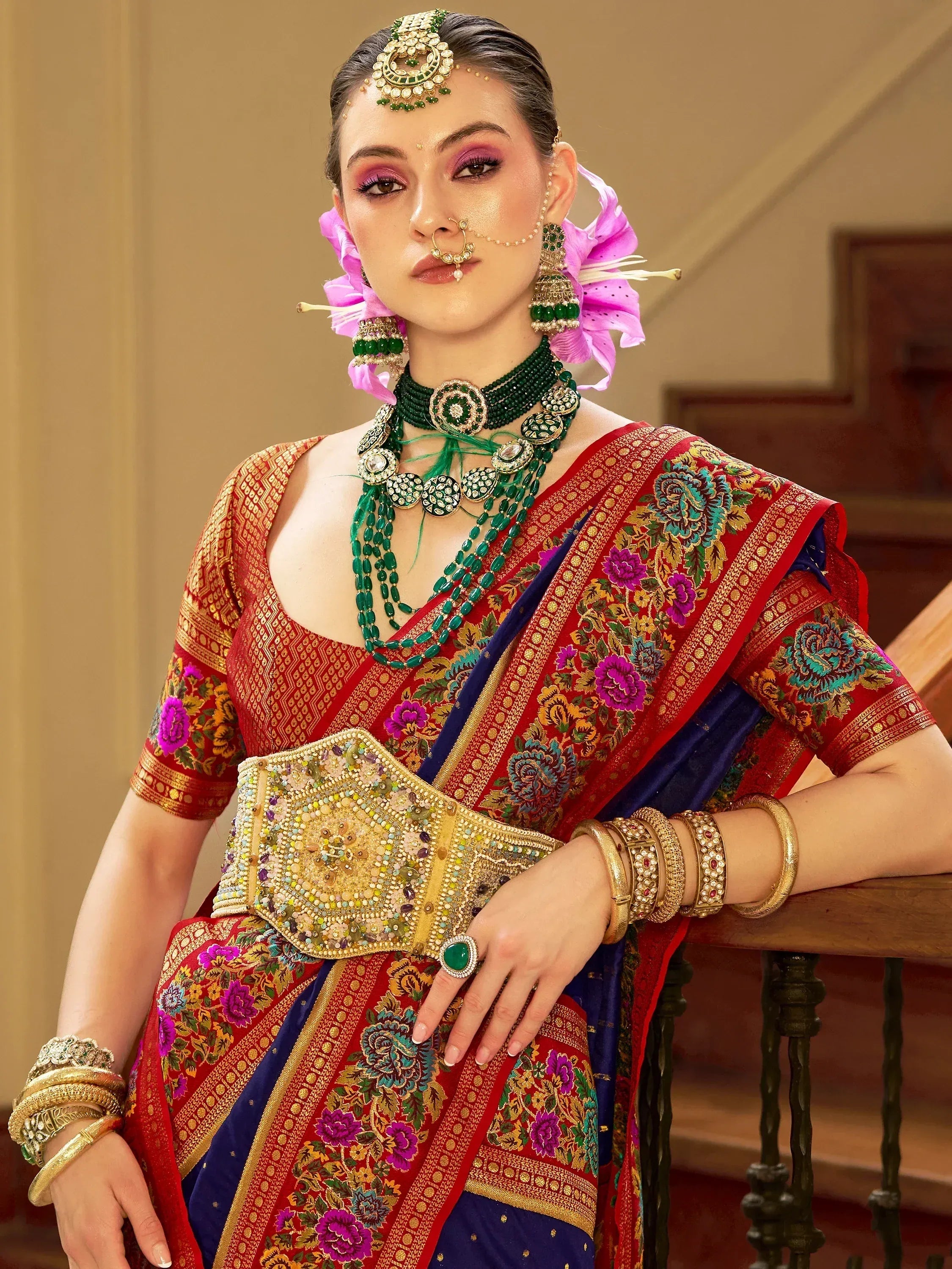 Woman in red and blue floral saree with green jewelry and floral hair accessory