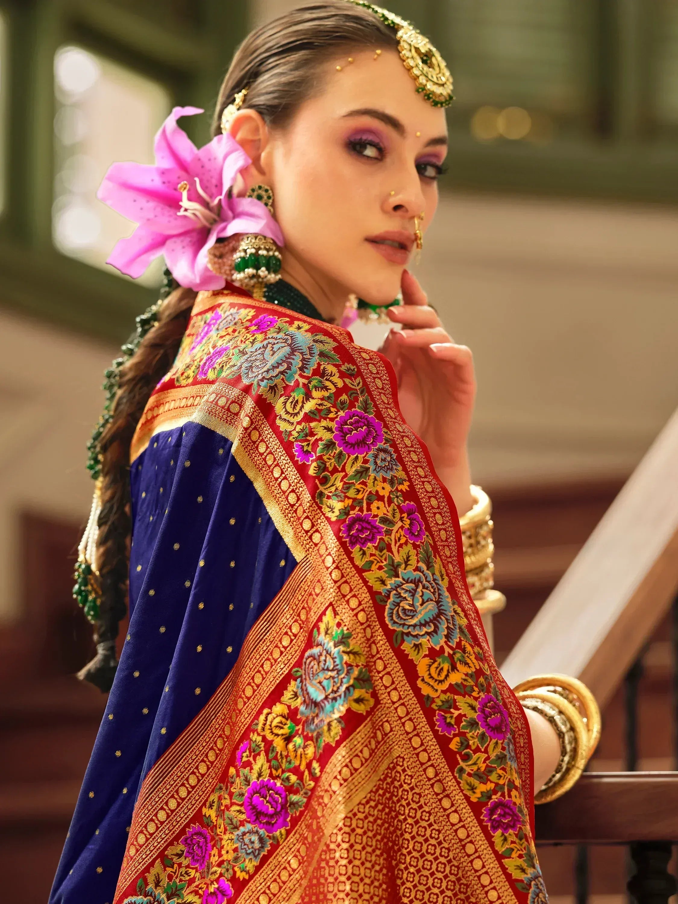 Woman in vibrant blue and red embroidered Indian ethnic wear with floral dupatta and gold jewelry