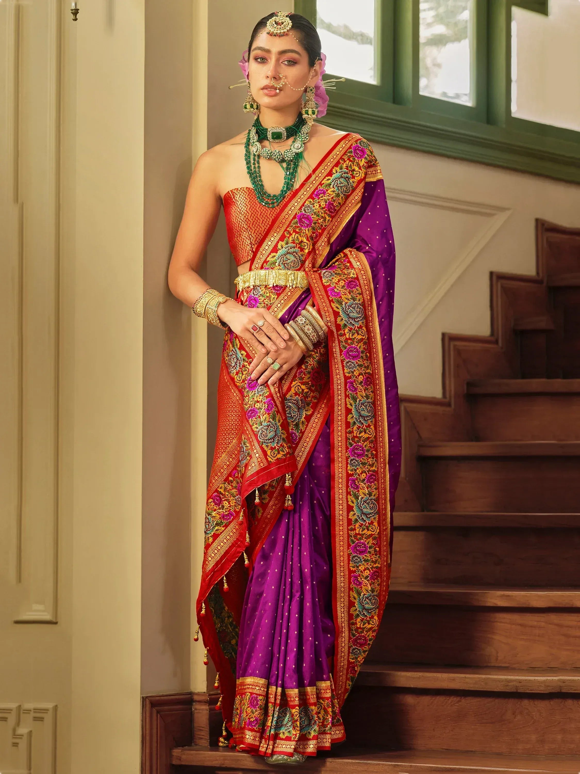 Purple and red embroidered saree with floral border, paired with green jewelry, ideal for Indian ethnic occasions.