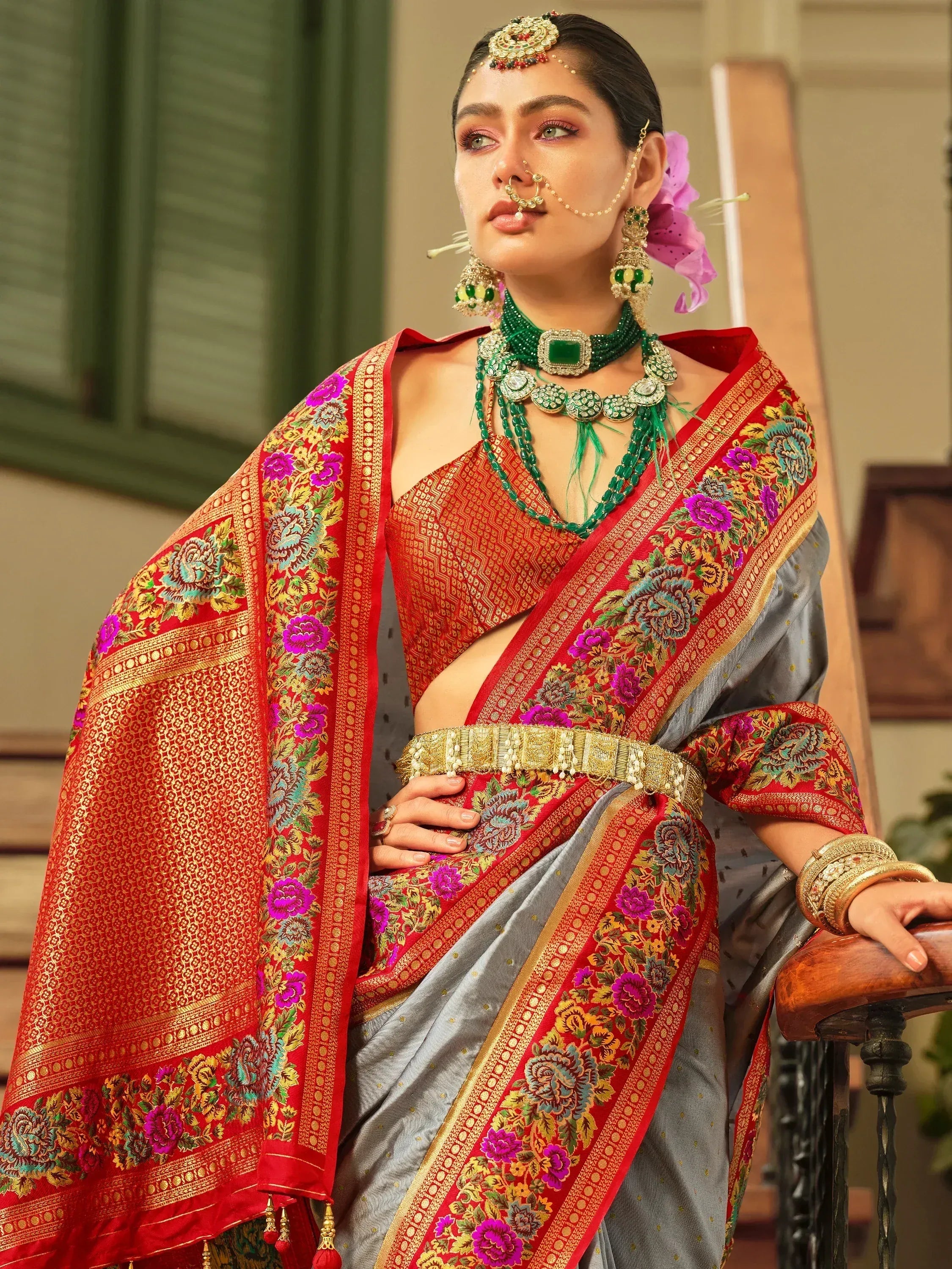 Woman in elegant grey and red embroidered saree with floral border, traditional Indian jewelry, and nose ring