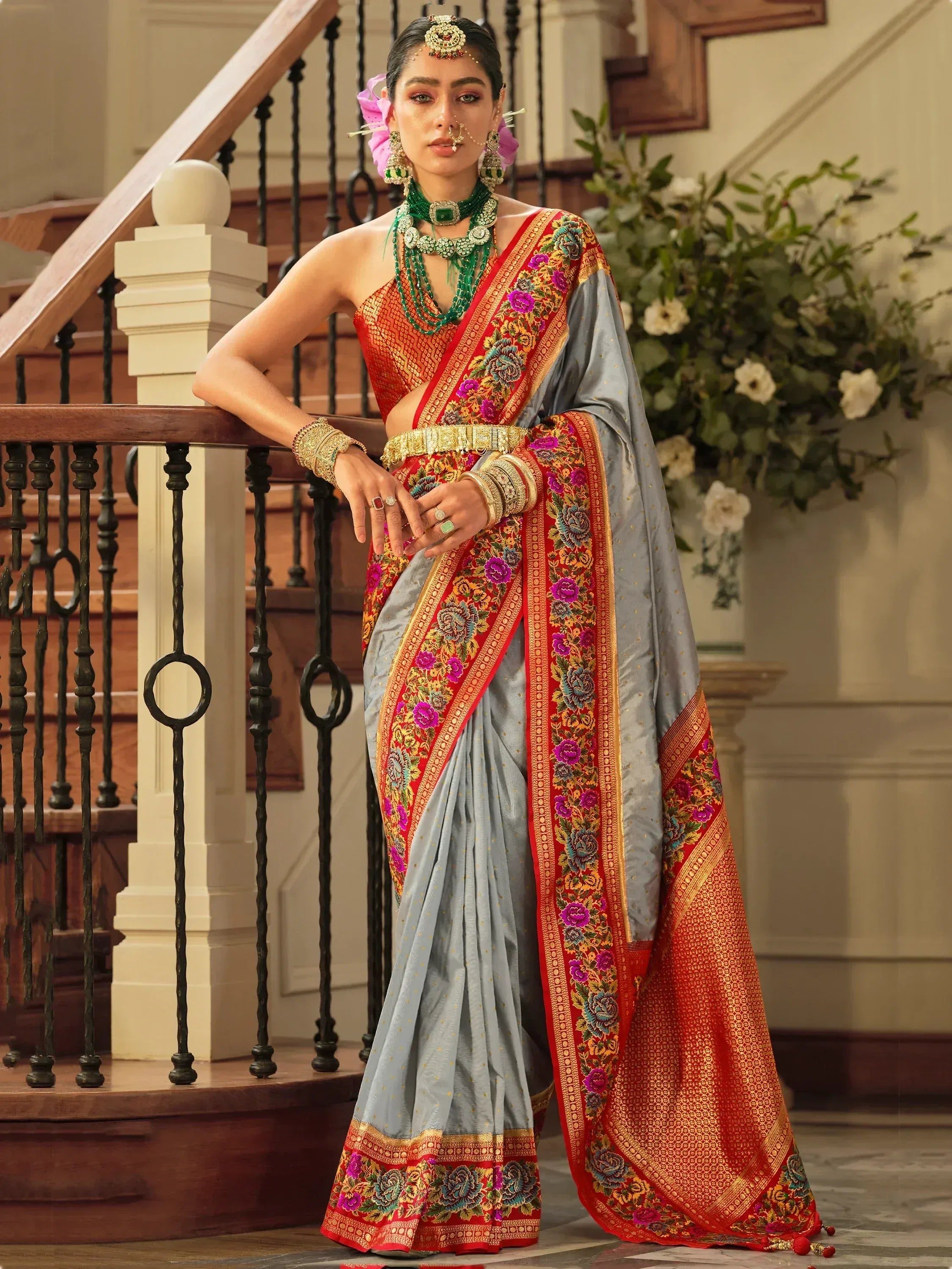 Elegant grey saree with red floral border, paired with green jewelry for festive Indian ethnic wear.