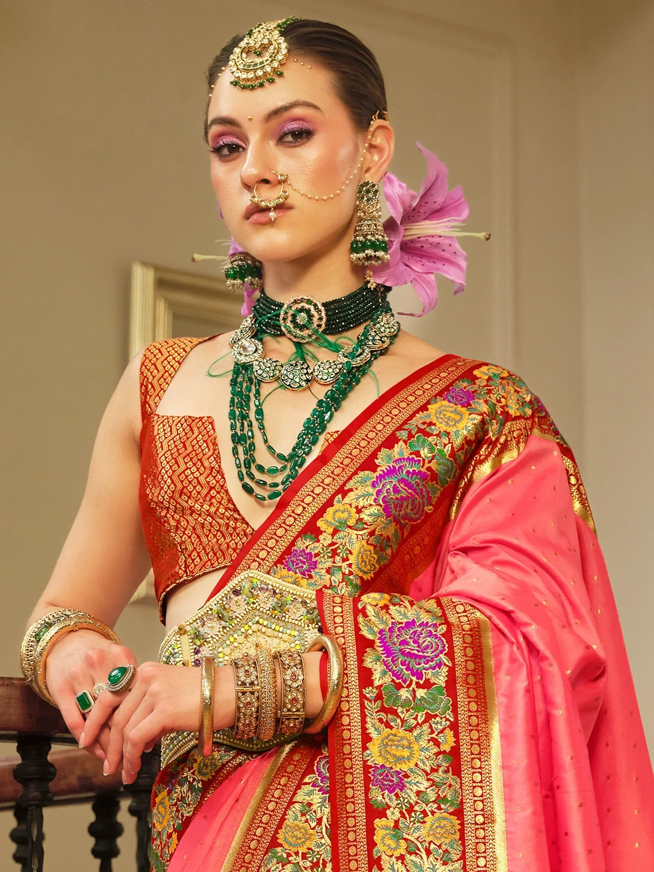 Woman in red and pink floral saree with green jewelry, traditional Indian ethnic wear