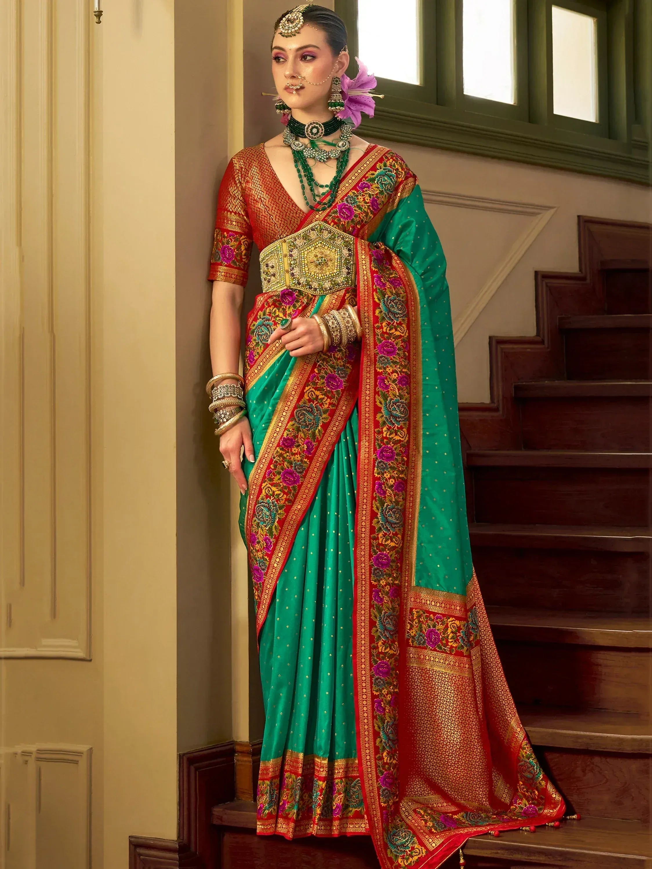 Woman in vibrant green and red embroidered saree with floral border, traditional Indian ethnic wear